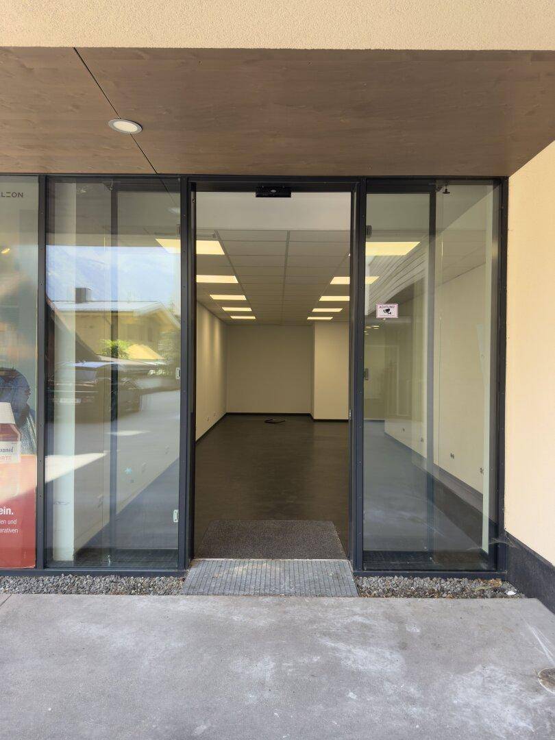 Eingangsbereich eines leeren Ladenlokals mit großer Glasfront und Blick in den hellen Innenraum.
