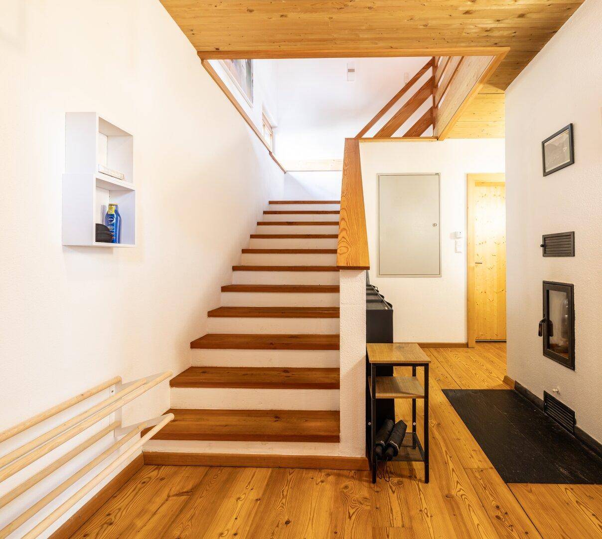 Heller Eingangsbereich mit Holztreppe und Holzboden, der zu den oberen Etagen führt.