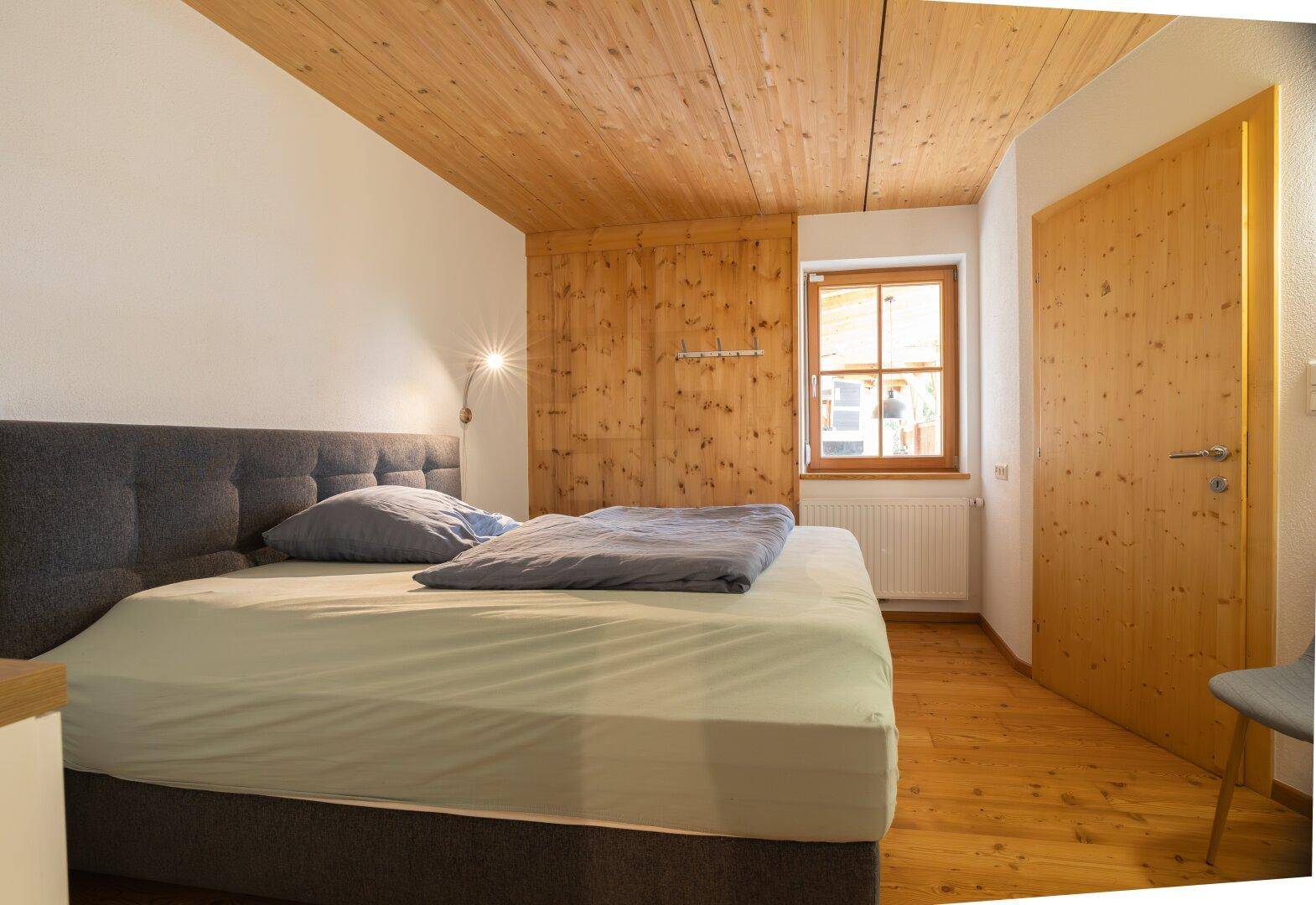 Gemütliches Schlafzimmer mit Holzboden, Holzdecke und großem Bett, ideal für Erholung.