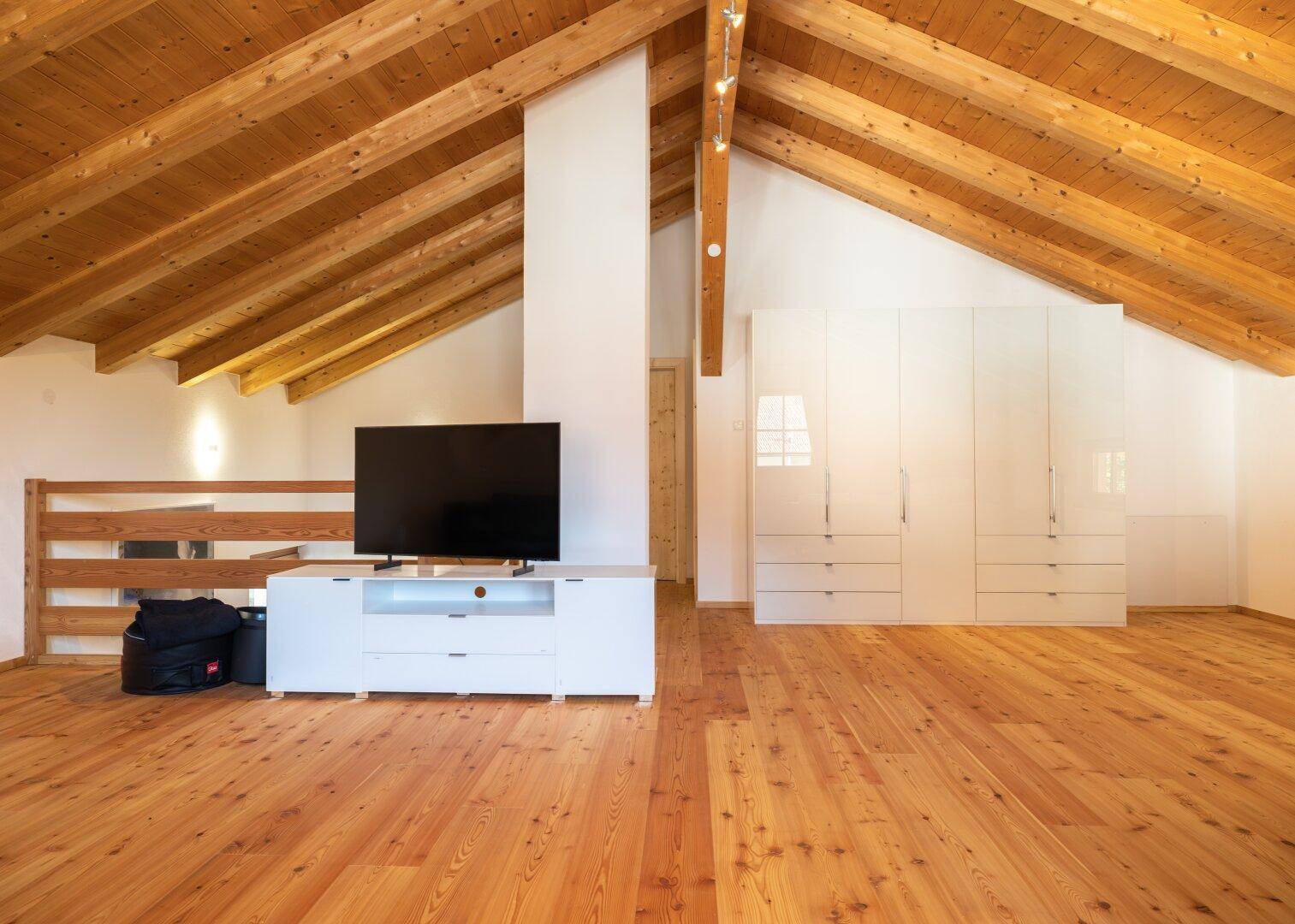 Geräumiges Schlafzimmer im Dachgeschoss mit Holzbalken, Holzboden und viel Stauraum.