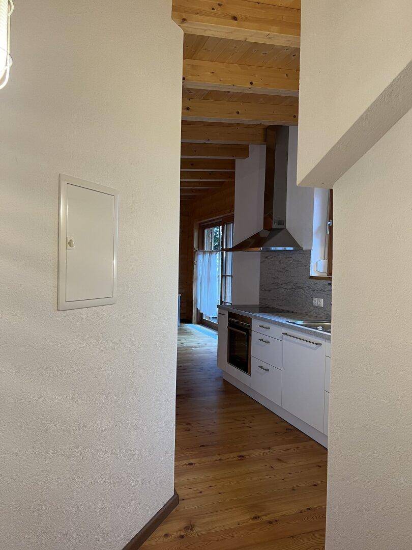 Flur mit Holzboden und Blick auf die moderne Küchenzeile und den Wohnbereich.
