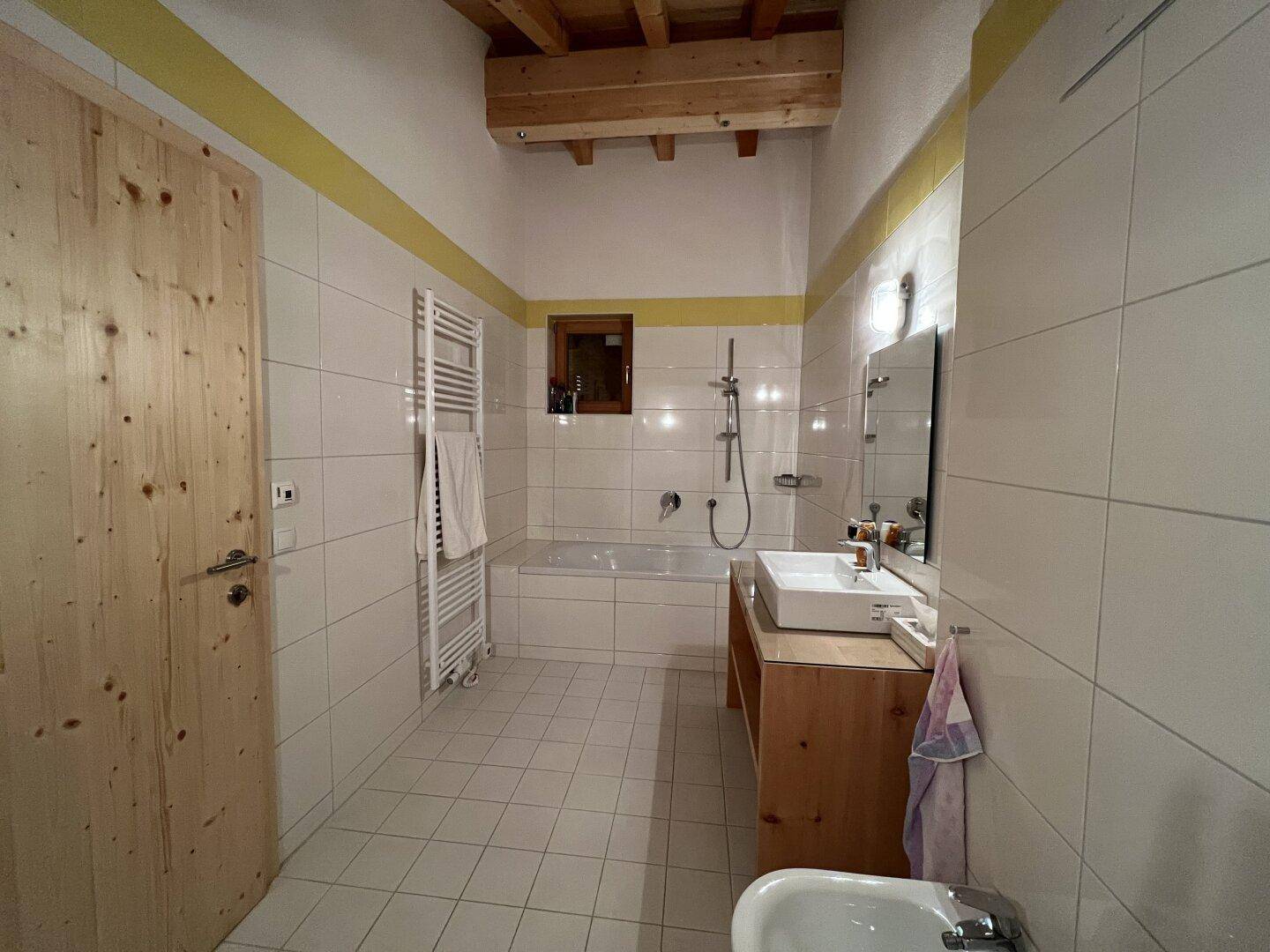 Geräumiges Badezimmer mit Badewanne, Bidet und gefliestem Boden, hell und funktional.