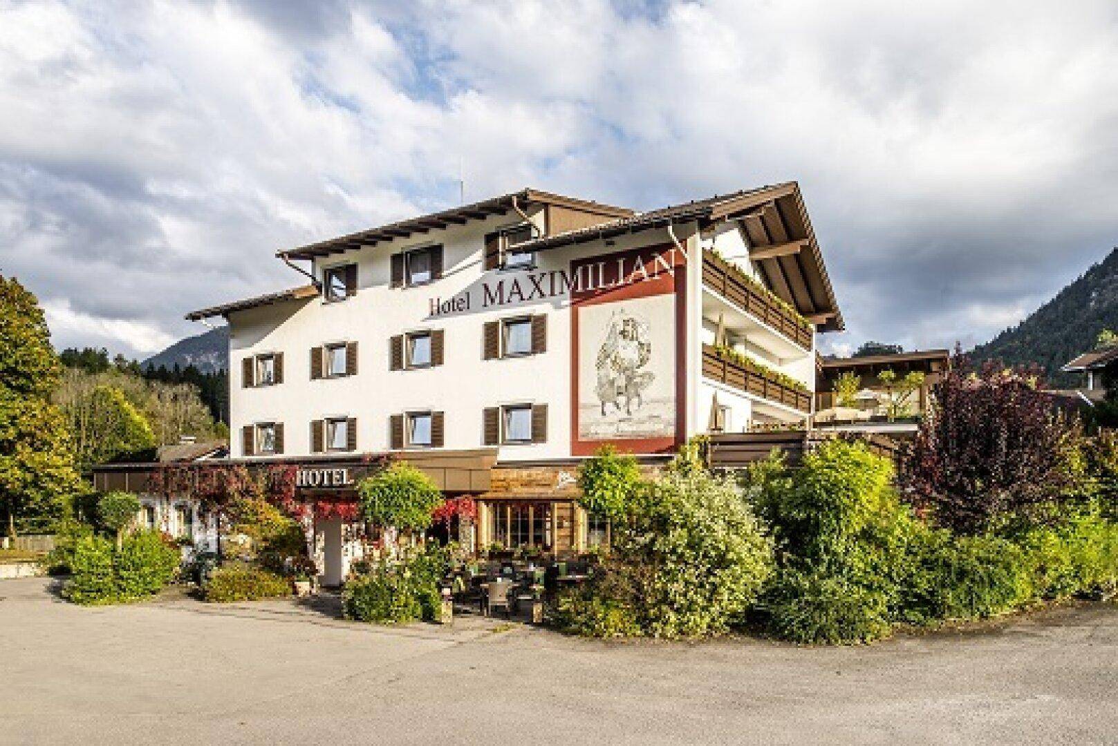 Das Hotel Maximilian präsentiert sich mit seiner charmanten Fassade und der malerischen alpinen Umgebung.