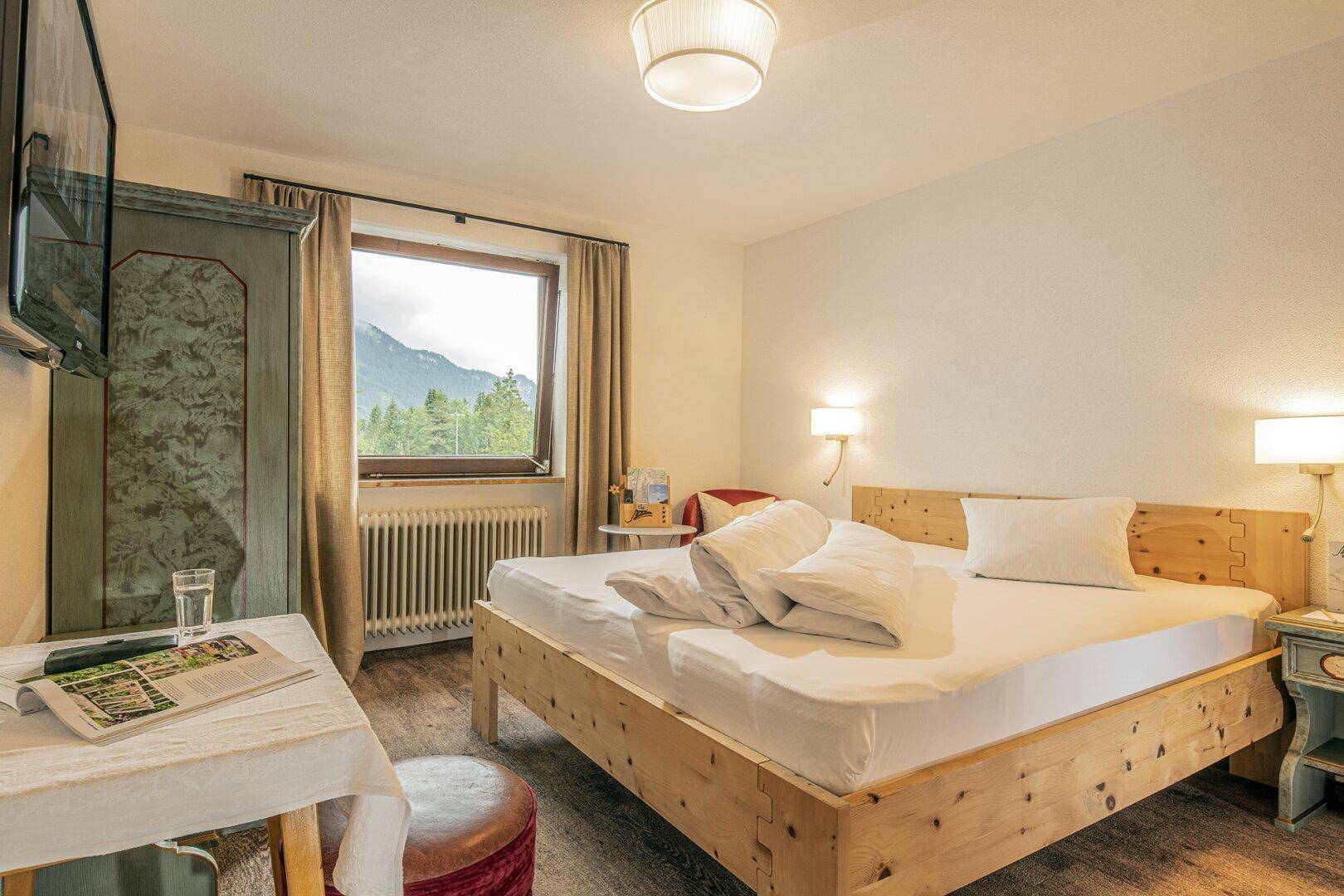 Rustikales Schlafzimmer mit Holzmöbeln, Laminatboden und einem großen Fenster mit Bergblick.