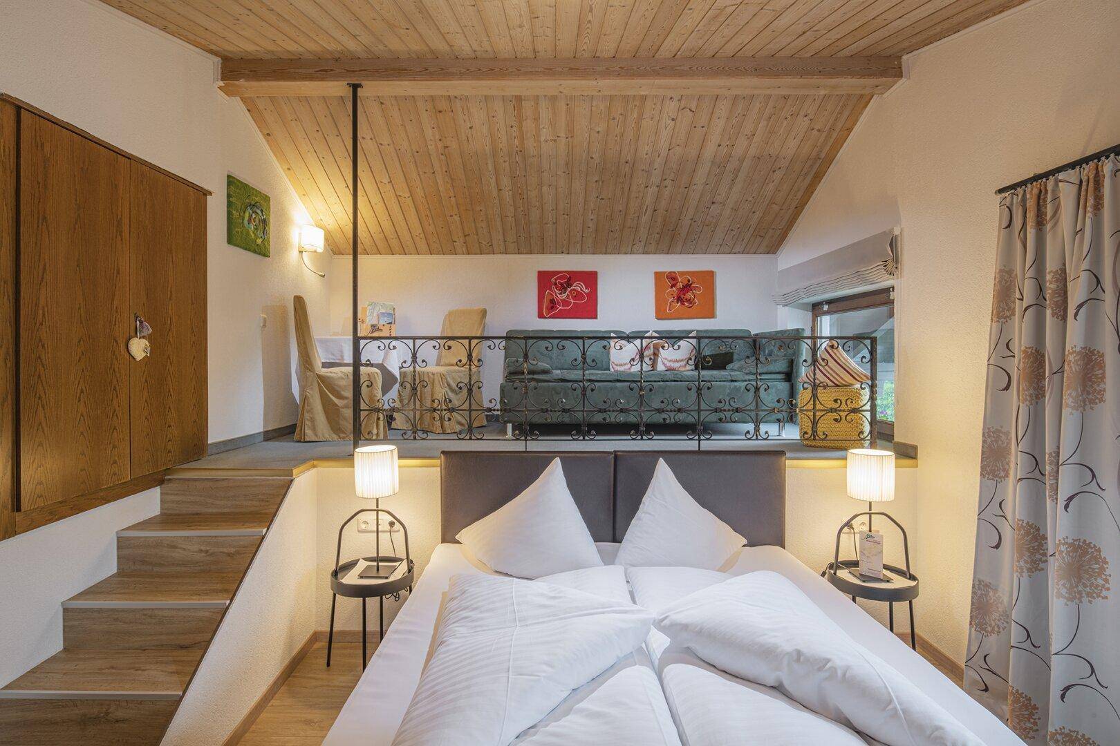 Schlafzimmer mit Doppelbett und einer erhöhten Galerie, die als gemütlicher Wohnbereich dient.