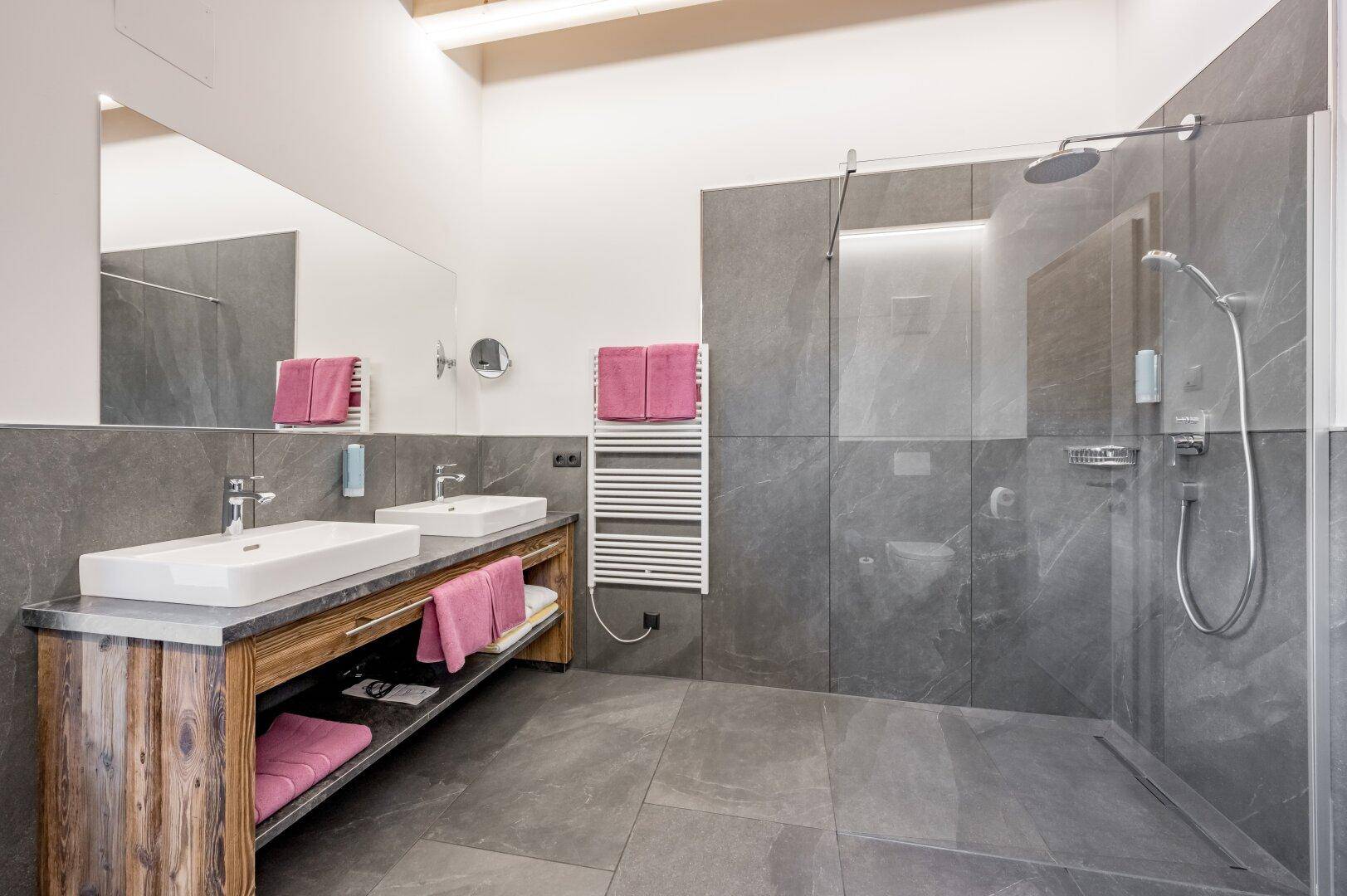 Elegantes Badezimmer mit Doppelwaschbecken, großem Spiegel und einer modernen, begehbaren Dusche.