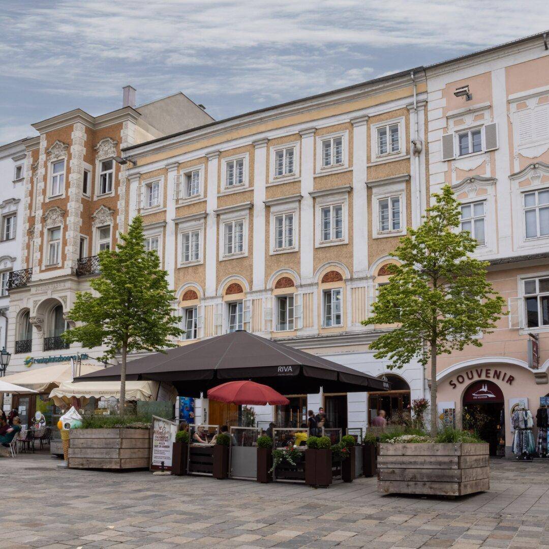 Historische Stadtfassade mit einem modernen Straßencafé und belebter Atmosphäre im Herzen der Stadt.