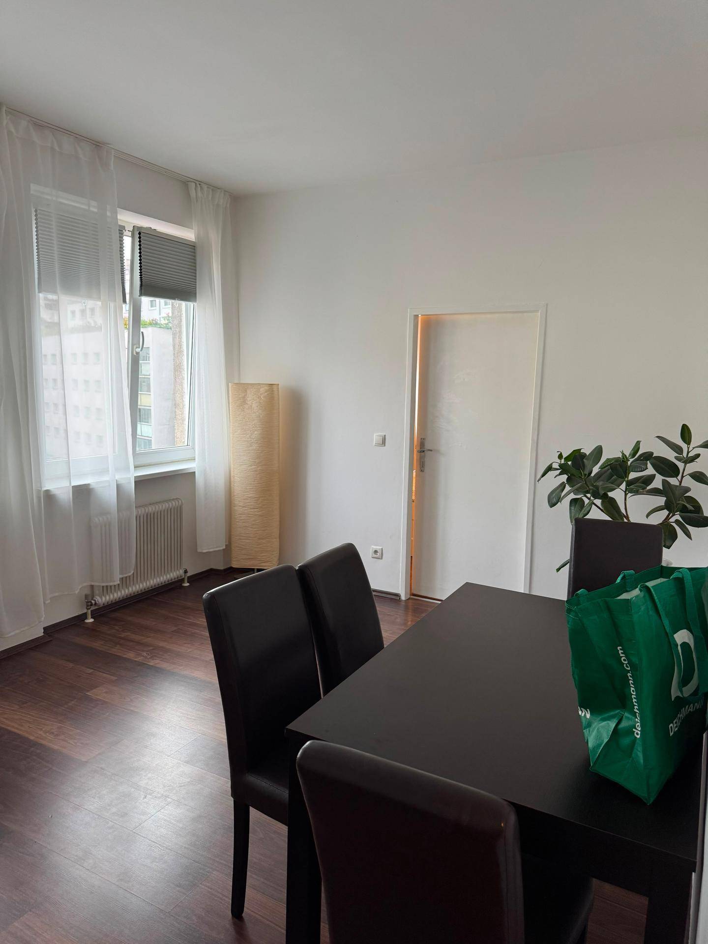 Essbereich mit dunklem Holztisch und Stühlen, viel Tageslicht durch große Fenster.