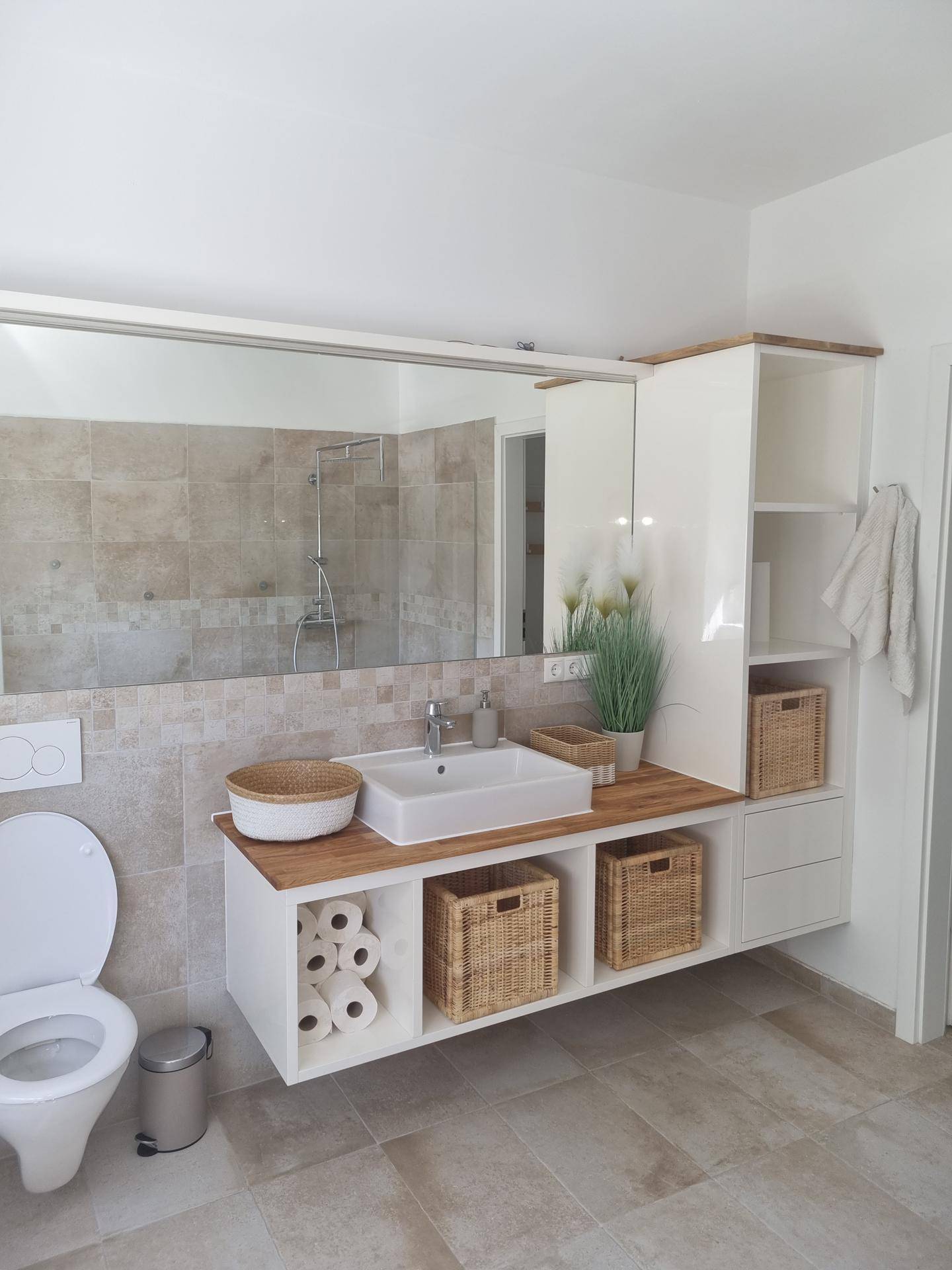 Modernes Badezimmer mit großem Waschtisch, integriertem Spiegel und begehbarer Dusche im Hintergrund.