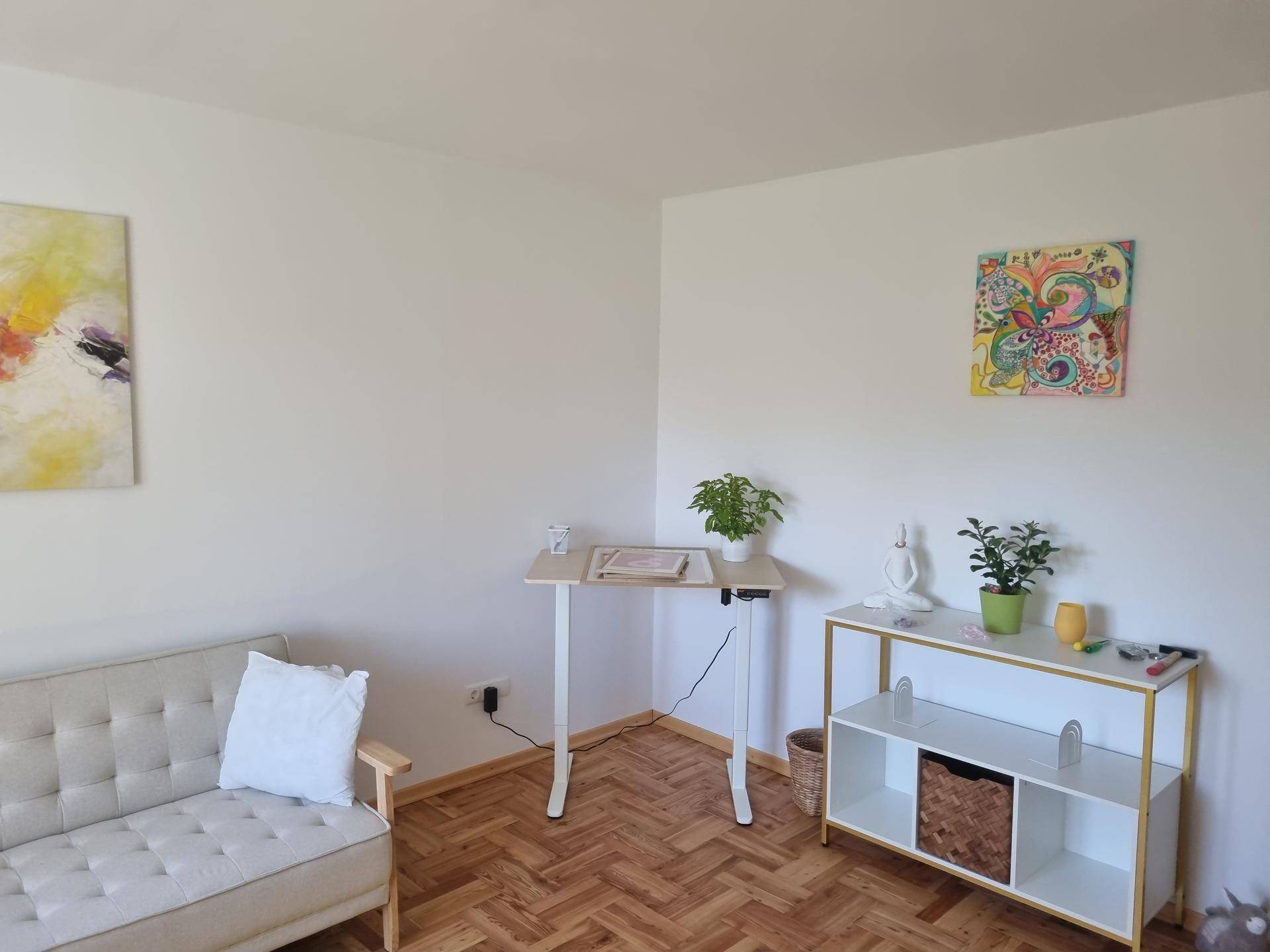 Heller Raum mit Fischgrätparkett, einem beigen Sofa und einem modernen Regal mit Dekoration.