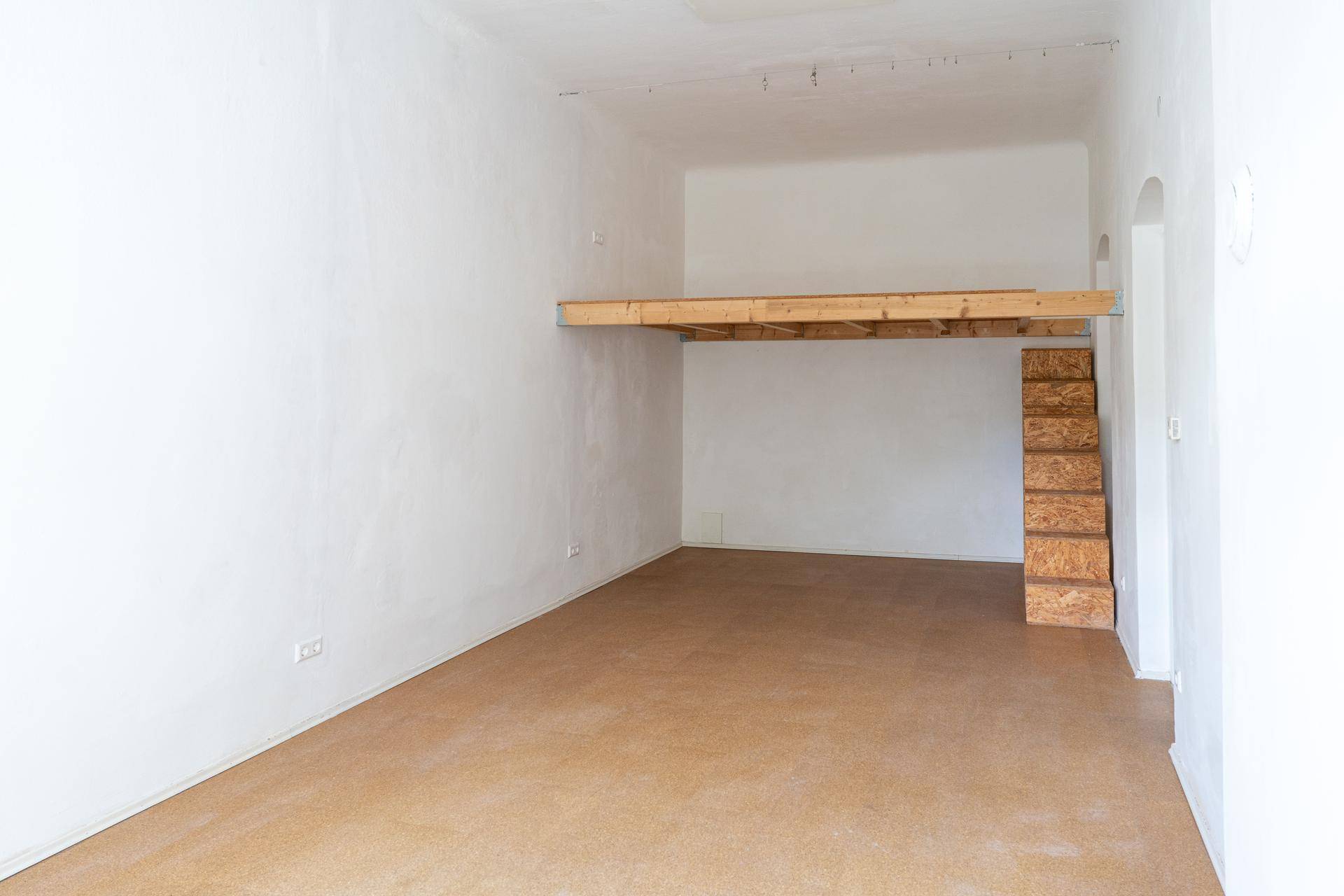 Geräumiger Raum mit einer neu errichteten Holzempore und passender Treppe.