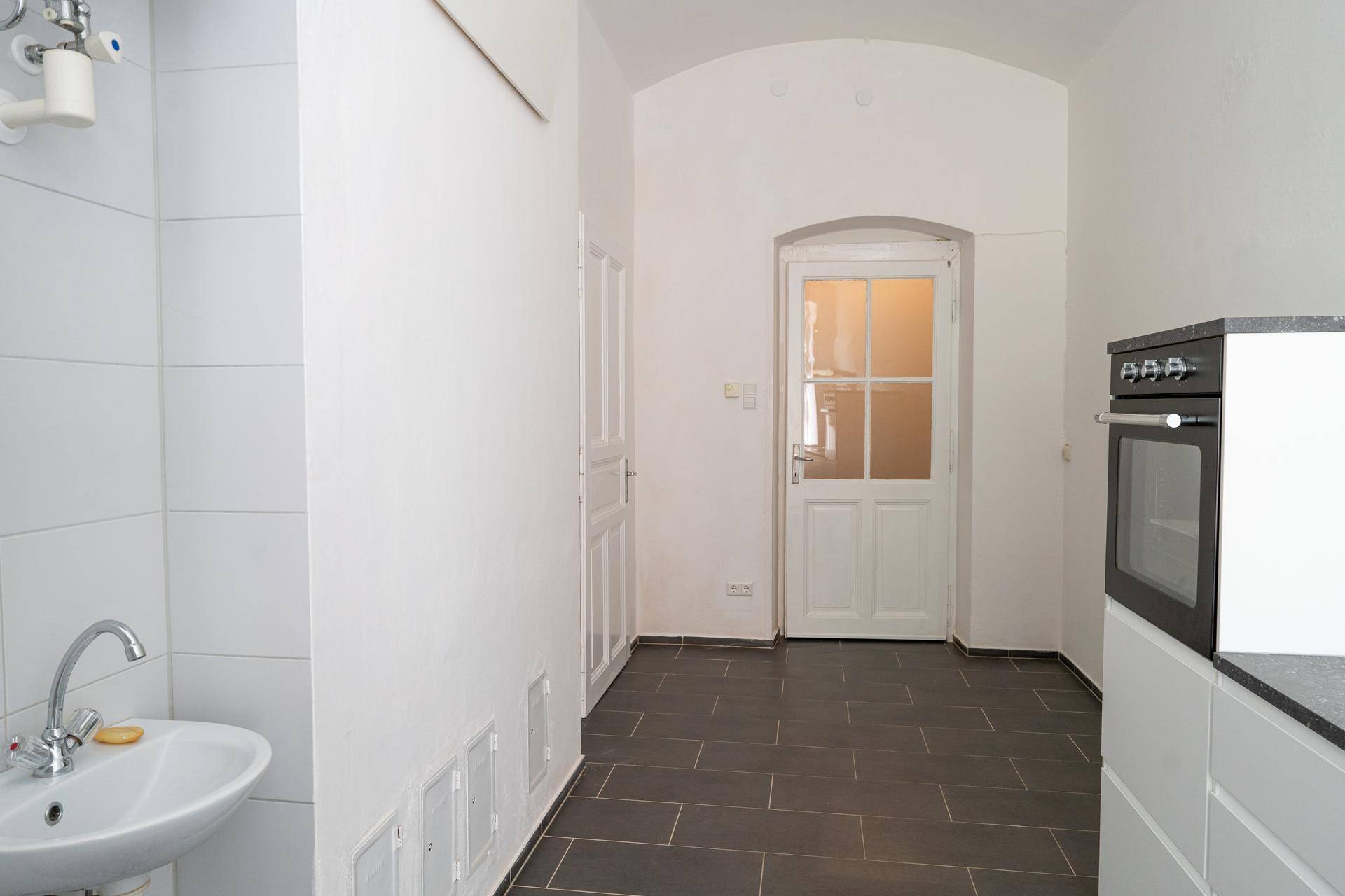 Flur mit gewölbter Decke, Zugangstür und einem kleinen Waschbecken im Eingangsbereich.