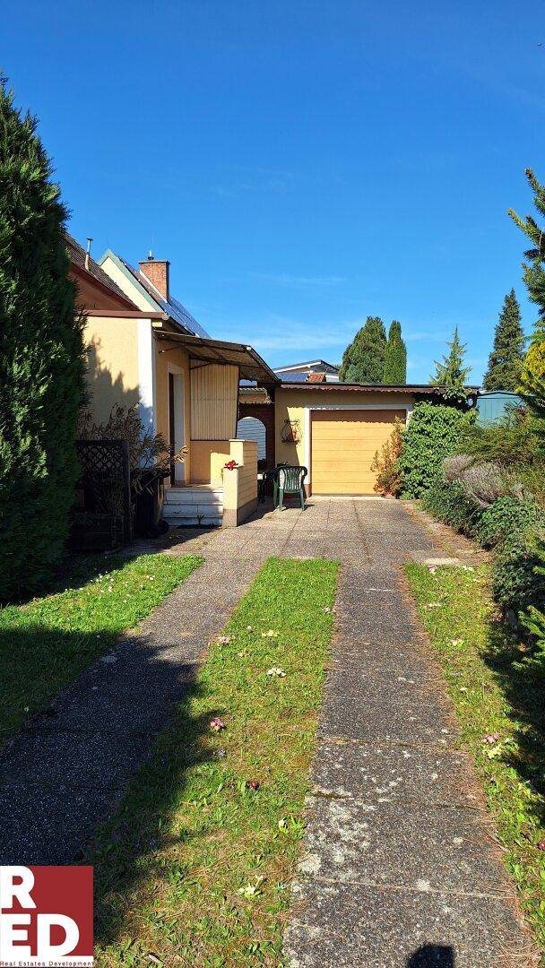Auffahrt zum Haus mit einer Garage und gepflegten Grünflächen entlang des Weges.