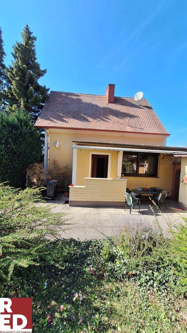 Rückseite des Hauses mit einer gepflasterten Terrasse und Sitzgelegenheiten im Freien.
