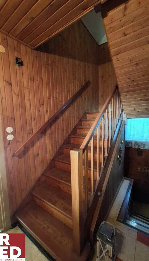 Rustikale Holztreppe mit Holzvertäfelung an Wänden und Decke, die in ein Obergeschoss führt.