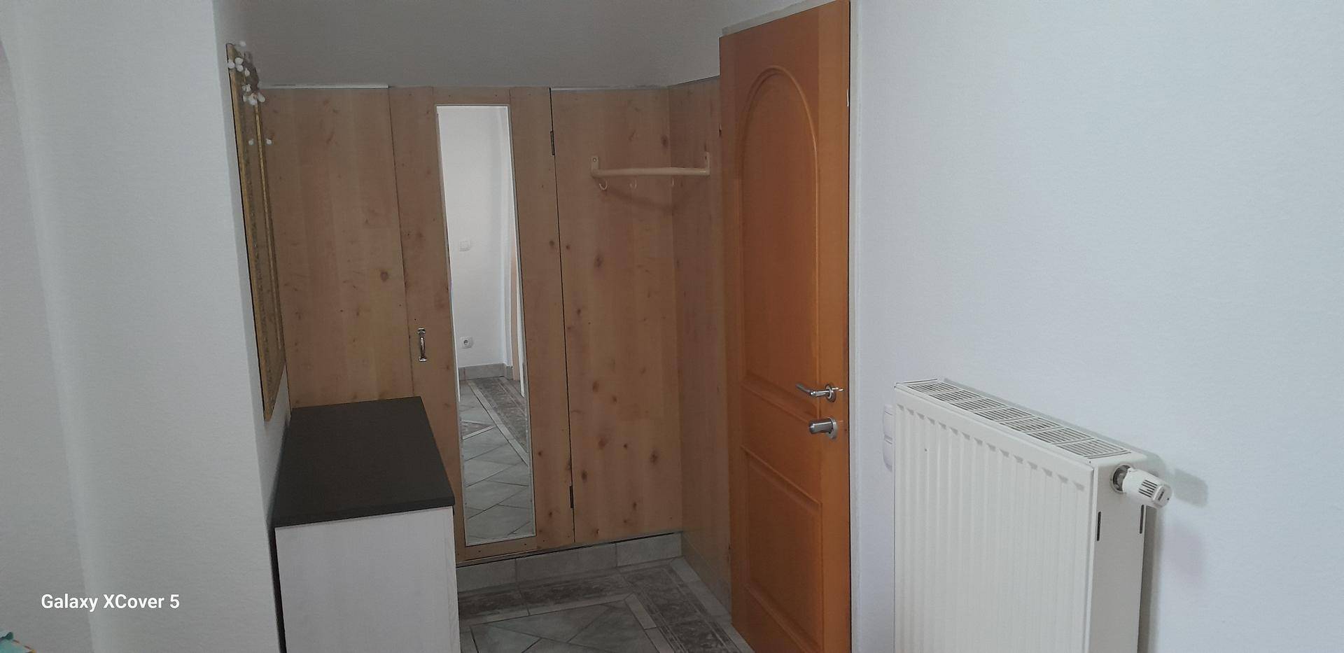 Flur mit integrierten Holzschränken, großem Spiegel und Heizkörper, bietet viel Stauraum.