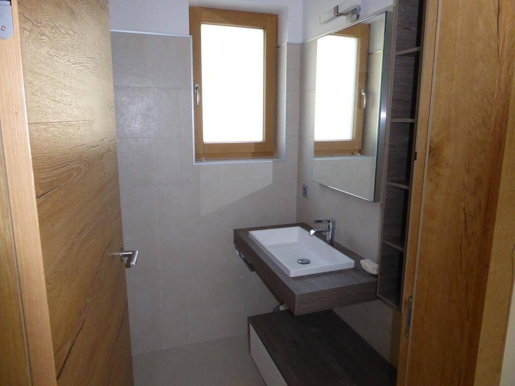 Kleines Badezimmer mit Einzelwaschbecken, Spiegelschrank und Fenster, in hellem Holzdesign.
