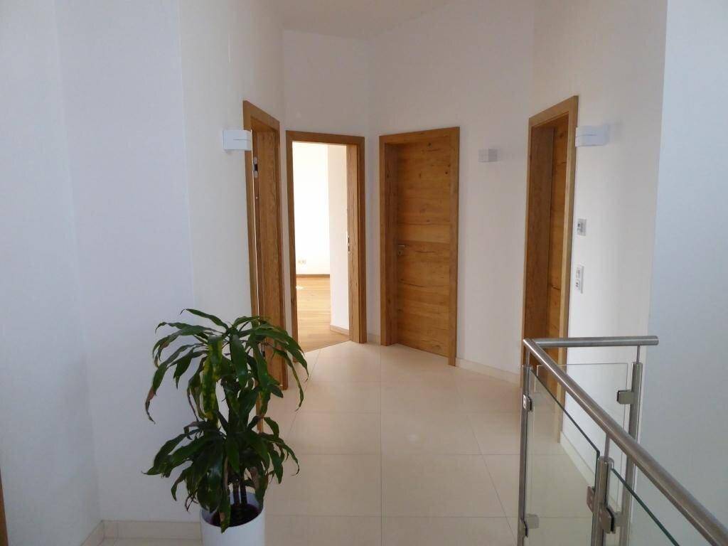 Heller Flur im Obergeschoss mit Holztüren, Fliesenboden und Blick auf weitere Zimmer.