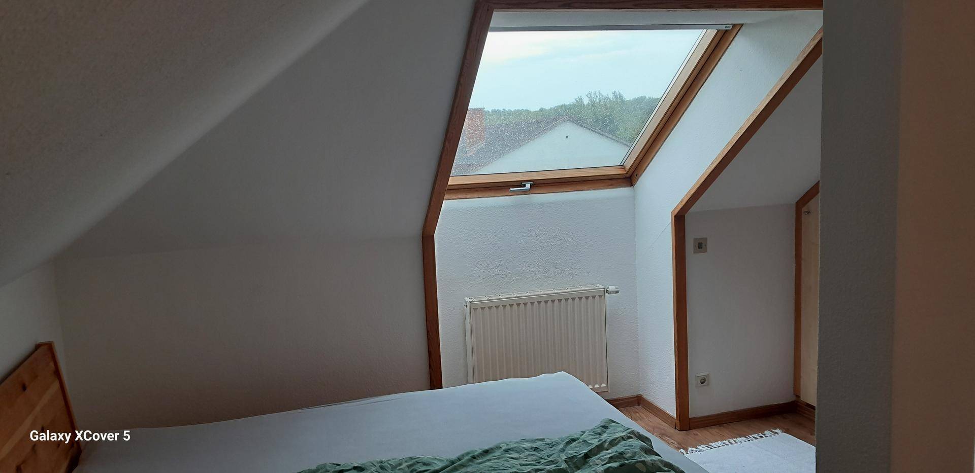 Helles Schlafzimmer im Dachgeschoss mit Dachfenster und Heizkörper, bietet eine gemütliche Atmosphäre.