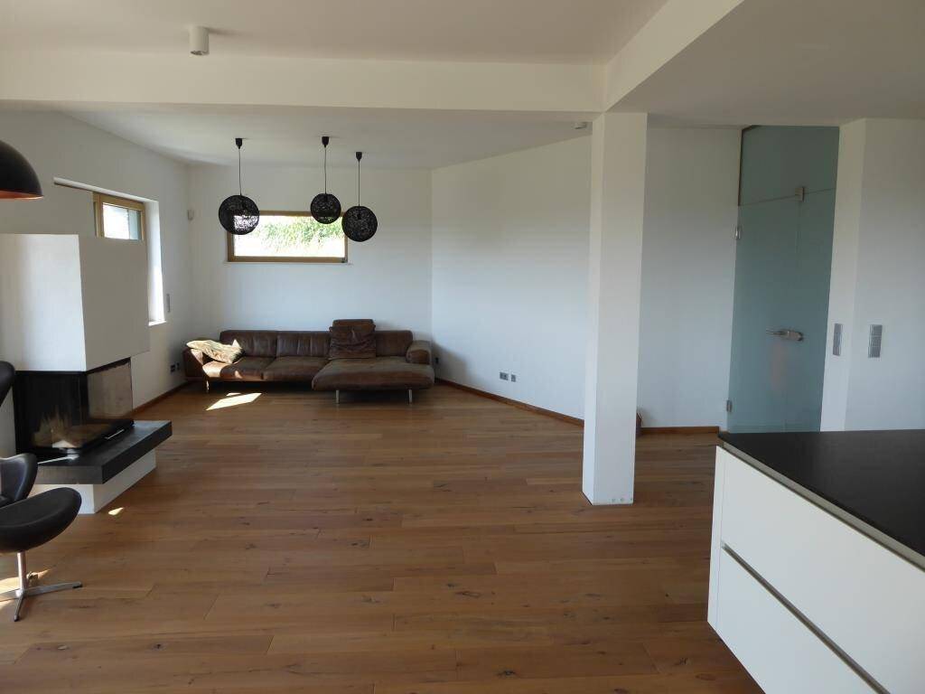 Gemütliches Wohnzimmer mit Holzboden, Kamin und bequemer Couch, offen zur Küche.