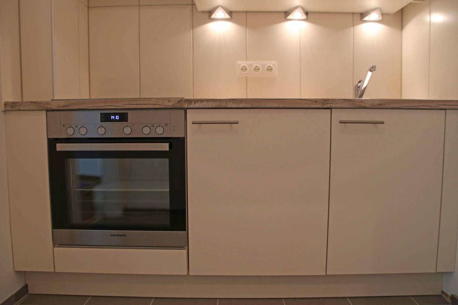 Detailansicht der Einbauküche mit Backofen, Spüle und Arbeitsplatte.