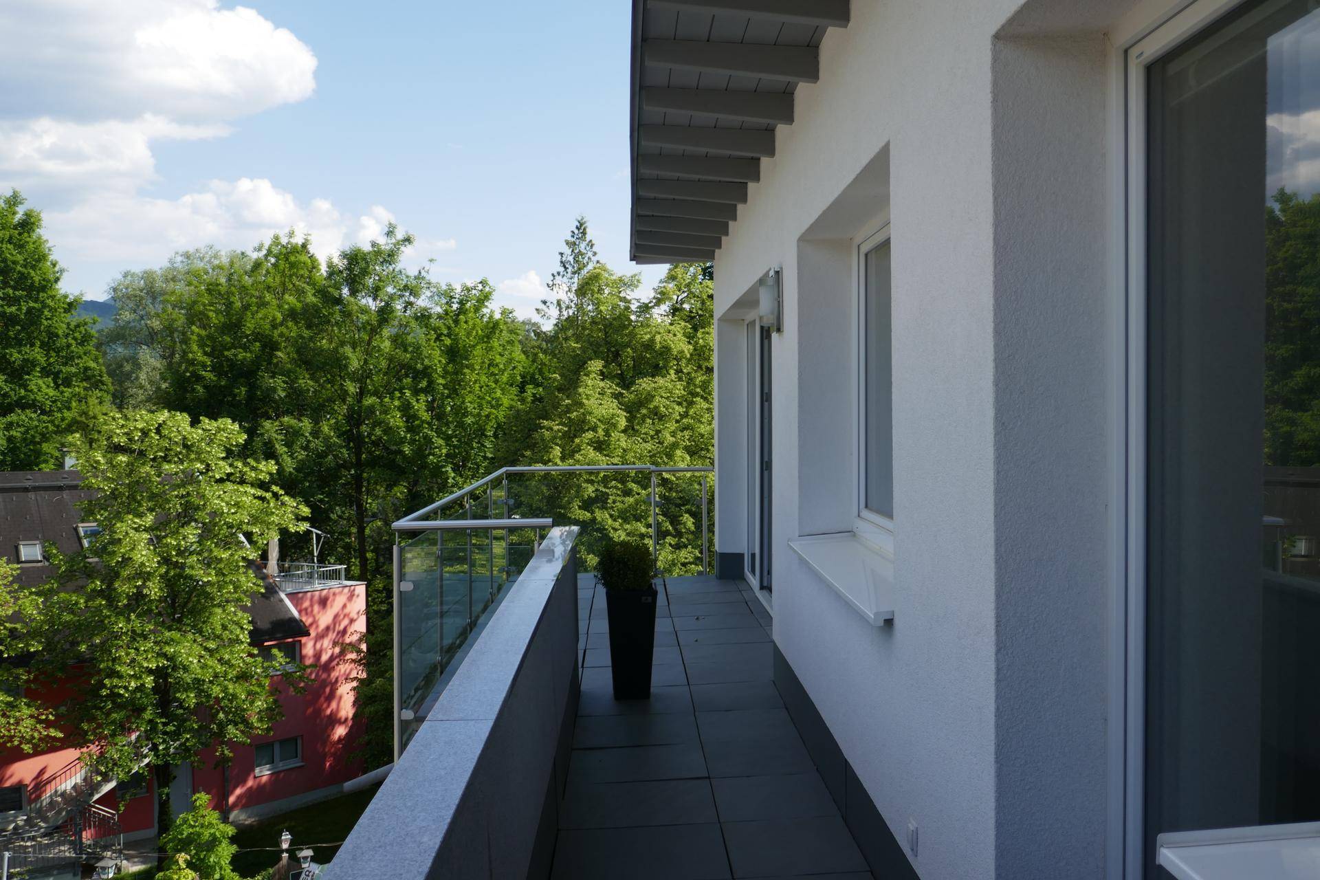Schmaler Balkon mit Glasgeländer und Blick ins Grüne, ideal für Entspannung im Freien.