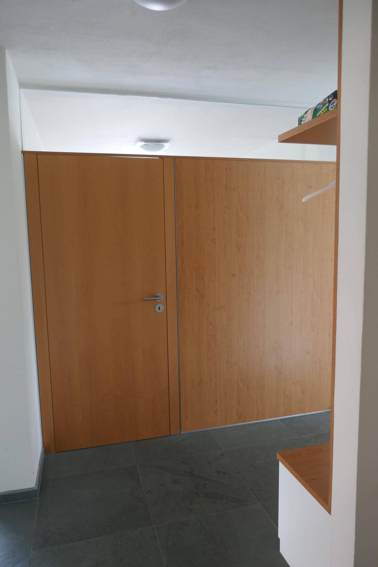Moderner Flur mit Holztüren und dunklem Fliesenboden, der zu weiteren Räumen führt.