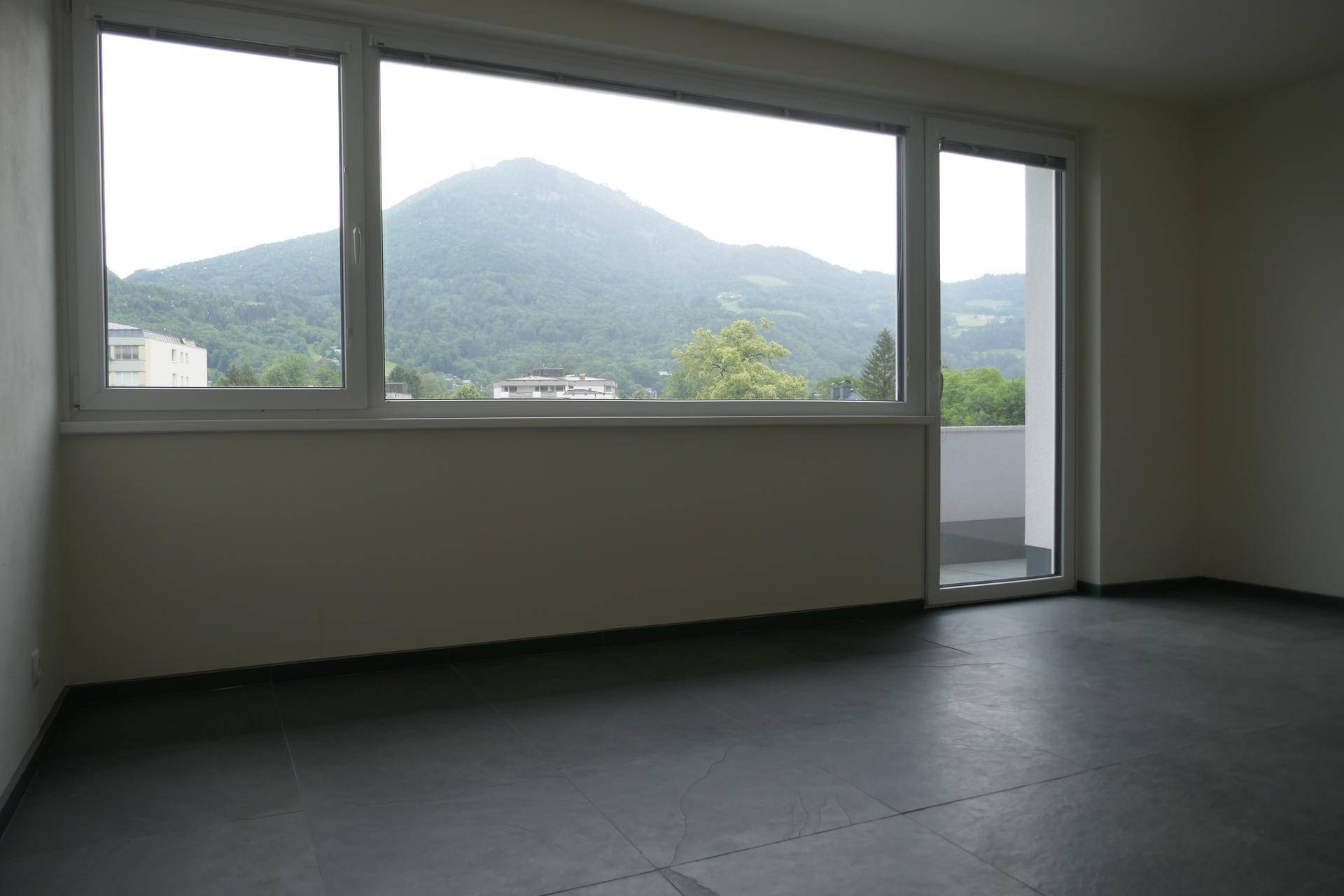 Geräumiger, heller Raum mit großen Fenstern und beeindruckendem Bergblick, bereit zur individuellen Gestaltung.