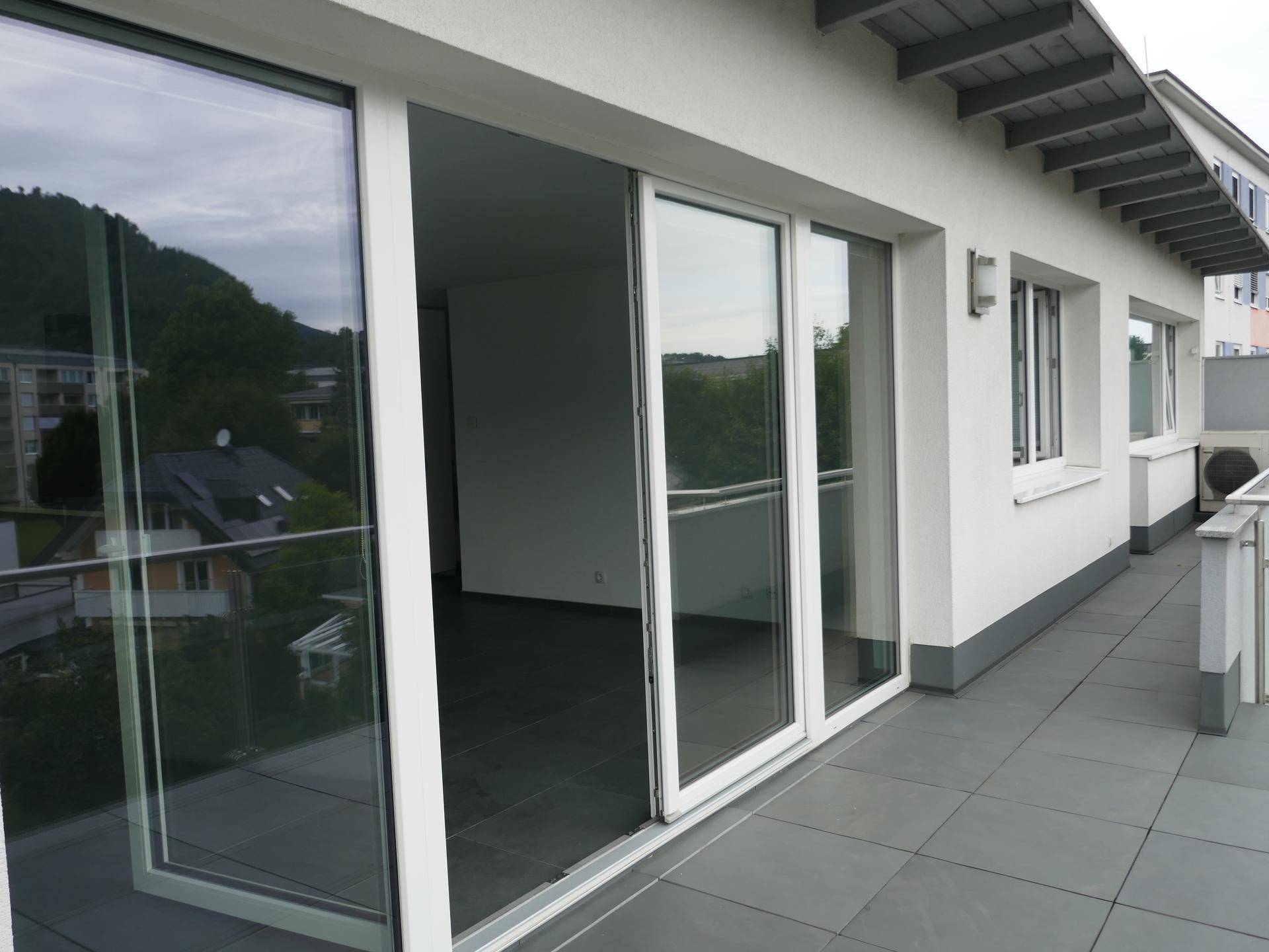Langer Balkon mit Schiebetüren und weitem Blick, der viel Tageslicht in die Innenräume lässt.