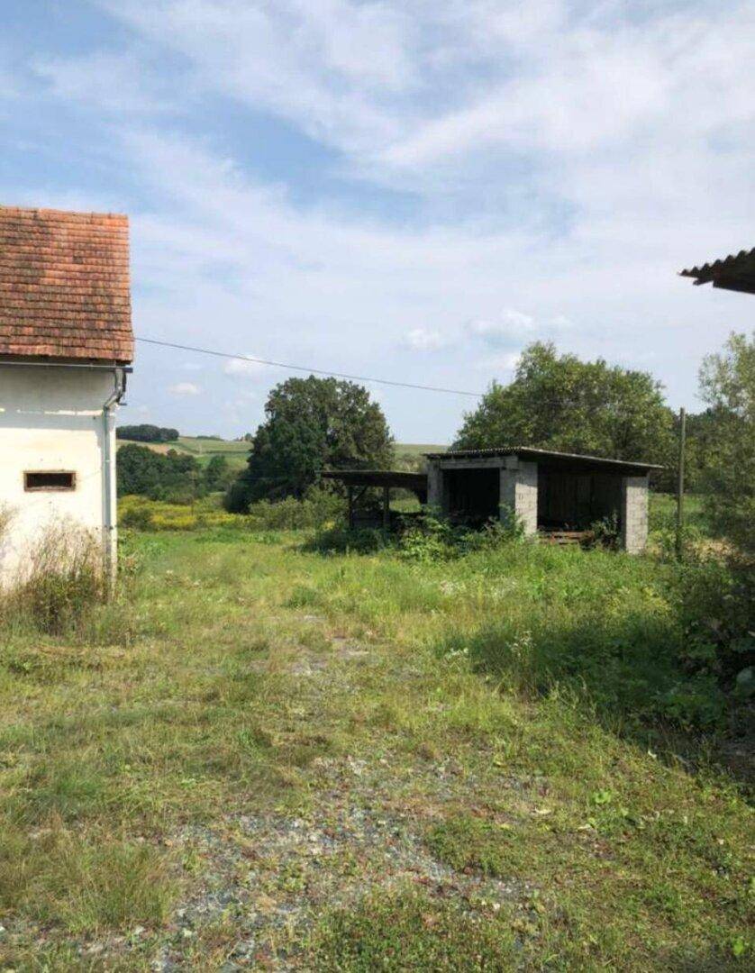 Ansicht des Wohnhauses und eines Nebengebäudes in ländlicher Umgebung mit viel Grün.