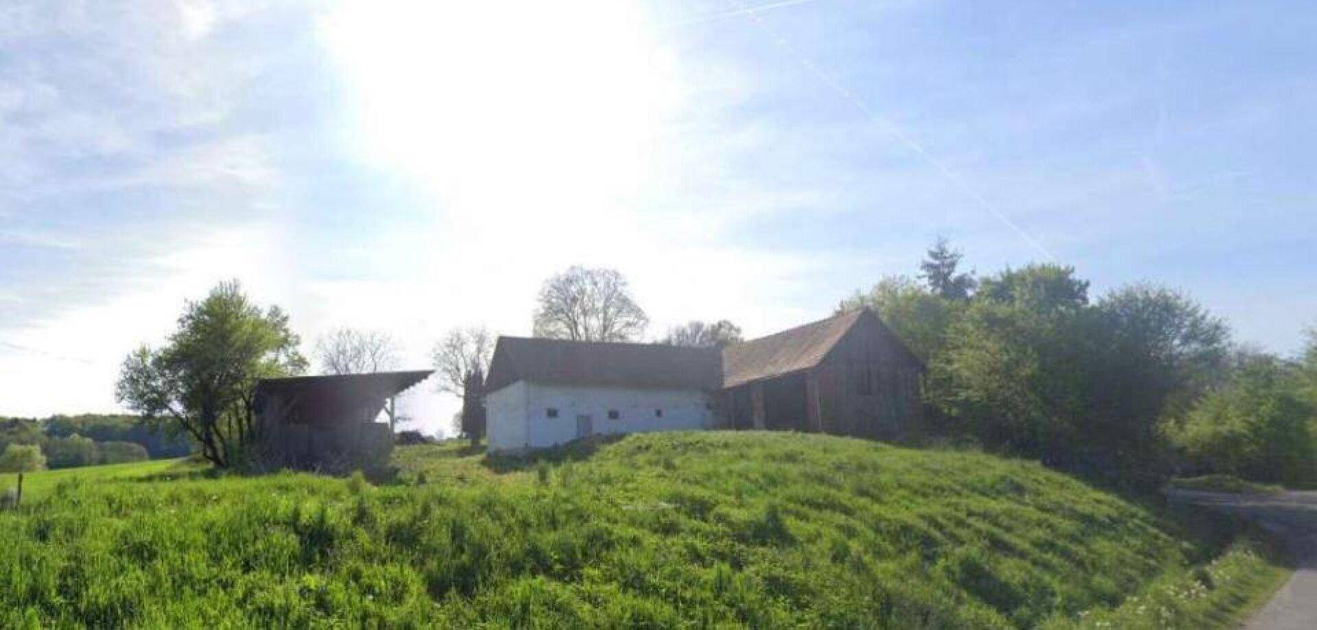 Weitläufige Ansicht des ländlichen Anwesens mit Nebengebäuden auf einer Anhöhe.