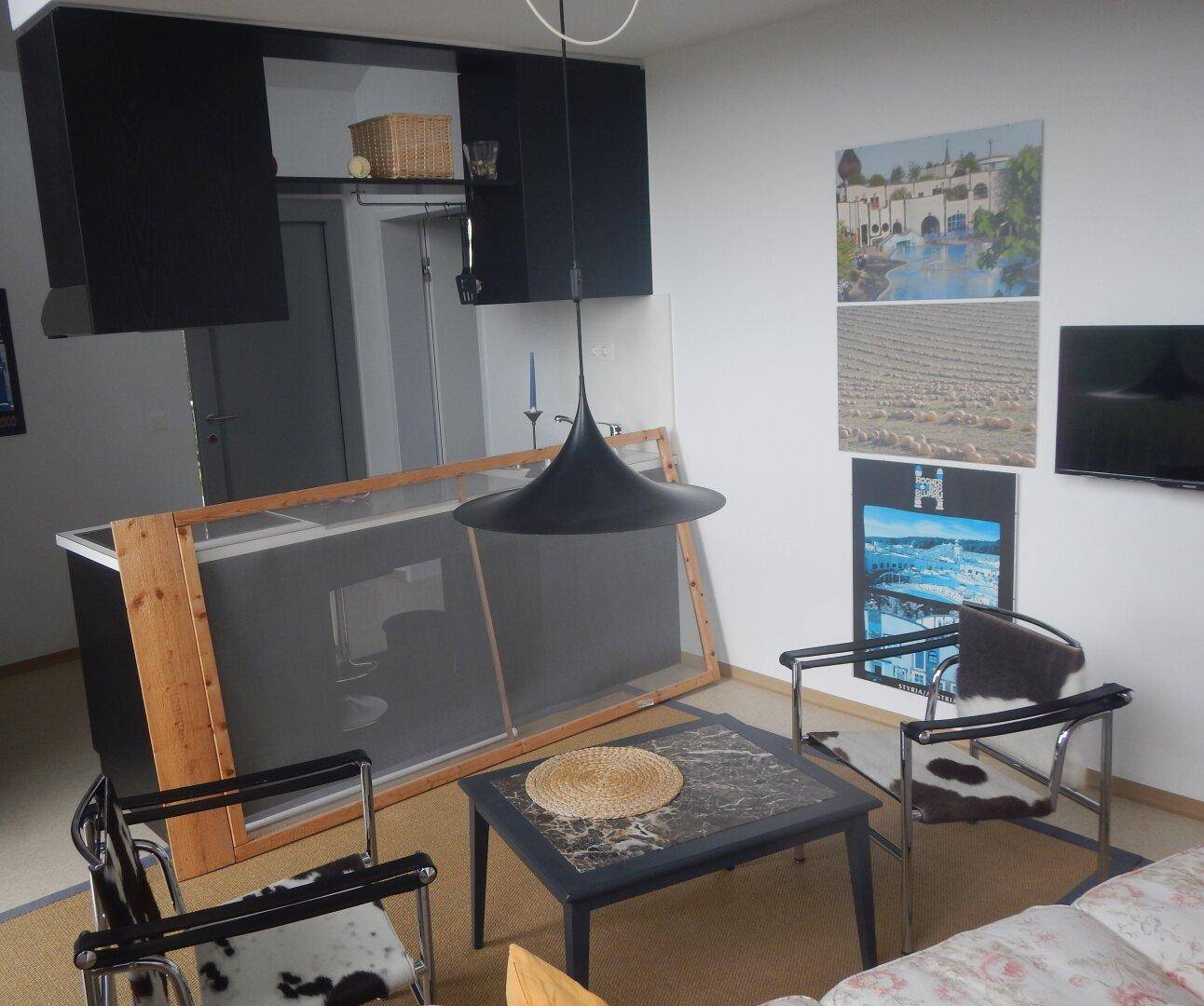 Gemütlicher Wohnbereich mit Sofa, Sesseln, Couchtisch und dekorativen Bildern an der Wand.
