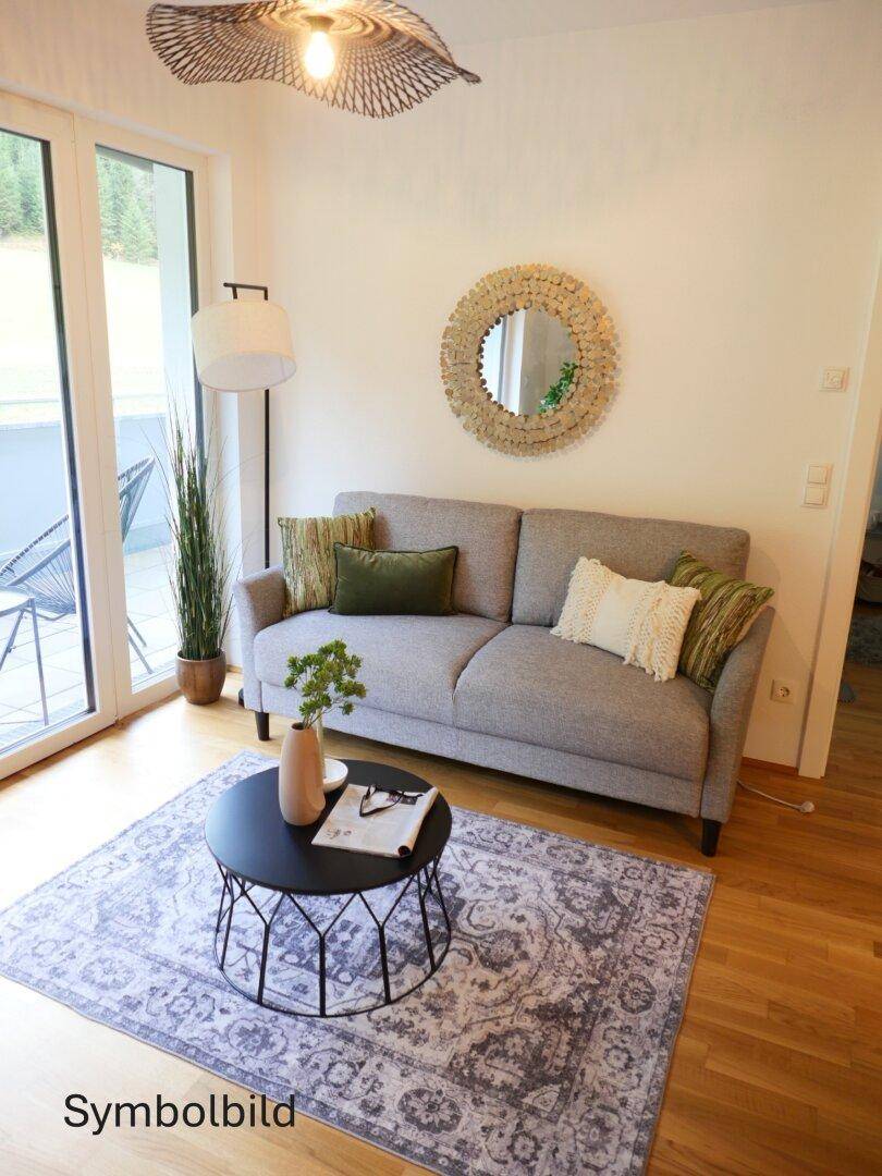 Helles Wohnzimmer mit modernem Sofa, Teppich und Zugang zu einem Balkon oder einer Terrasse.