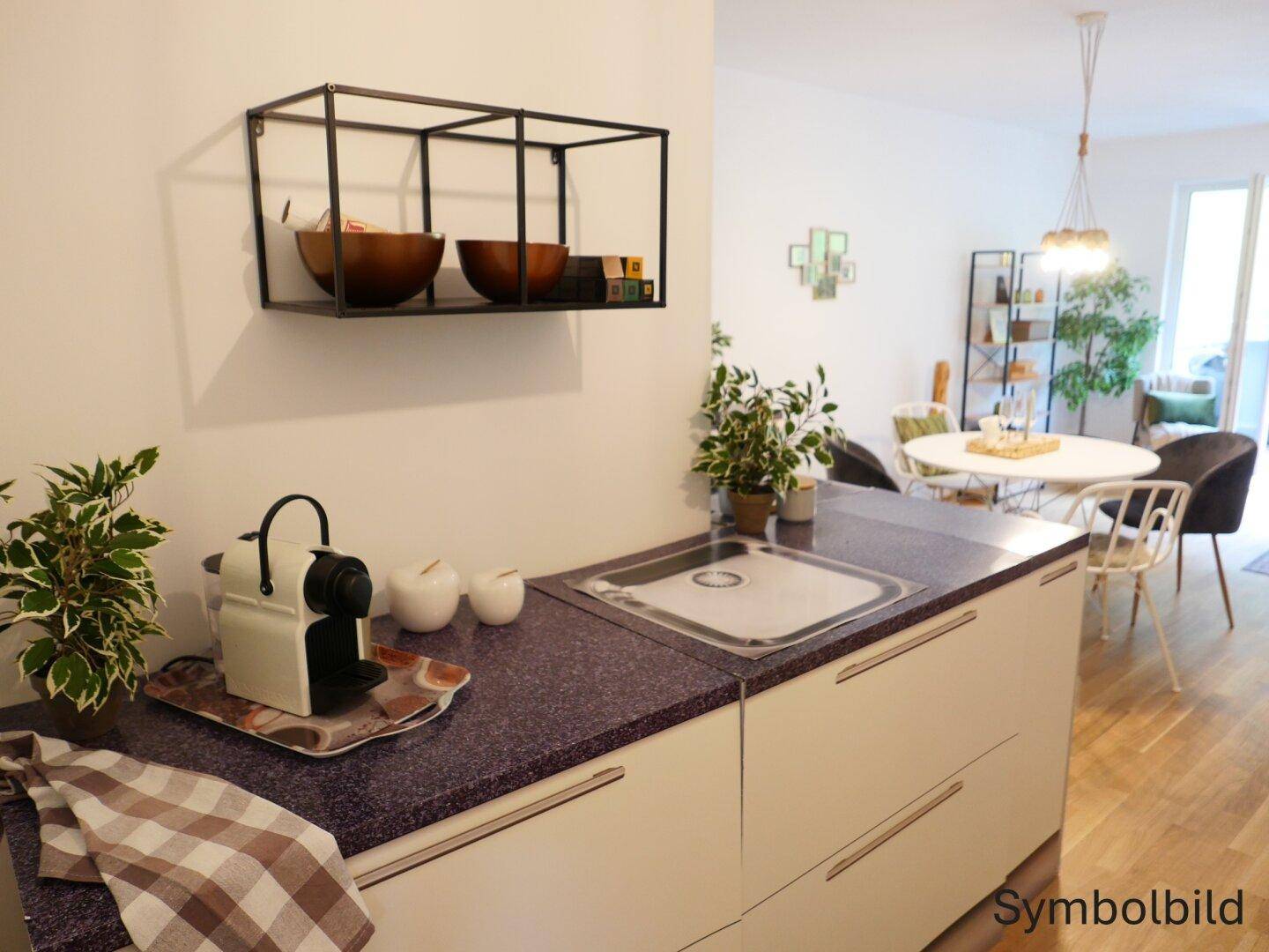 Moderne Küchenzeile mit Spüle, Kaffeemaschine und Blick auf den offenen Essbereich.