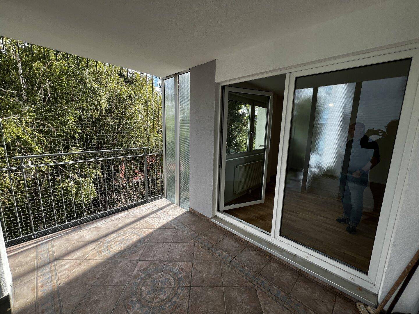 Geräumiger Balkon mit Fliesenboden und Blick ins Grüne, ideal zum Entspannen im Freien.