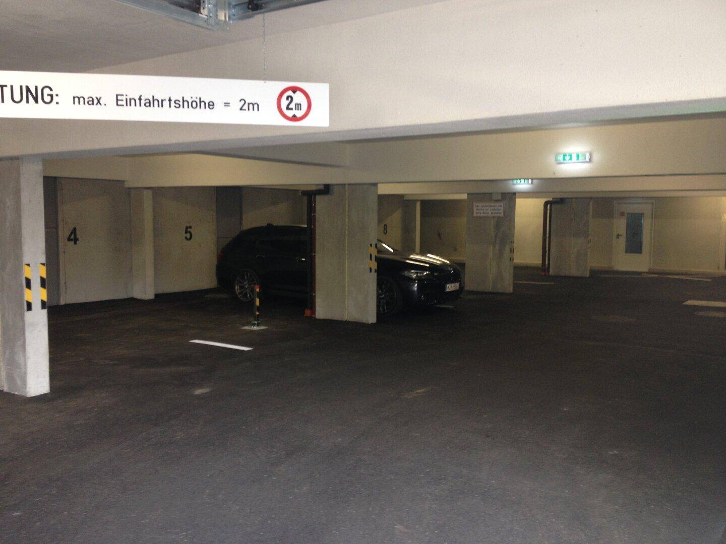 Geräumige Tiefgarage mit Betonstützen, asphaltiertem Boden und einer Höhenbegrenzung von 2 Metern.