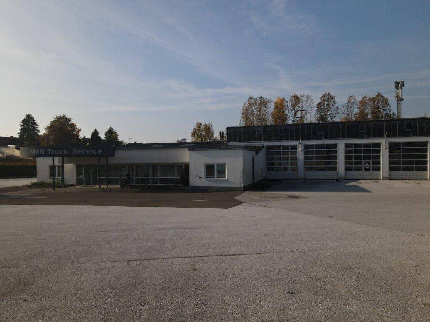 Vorderansicht eines Gewerbegebäudes mit Bürobereich und mehreren Garagentoren für Servicefahrzeuge.