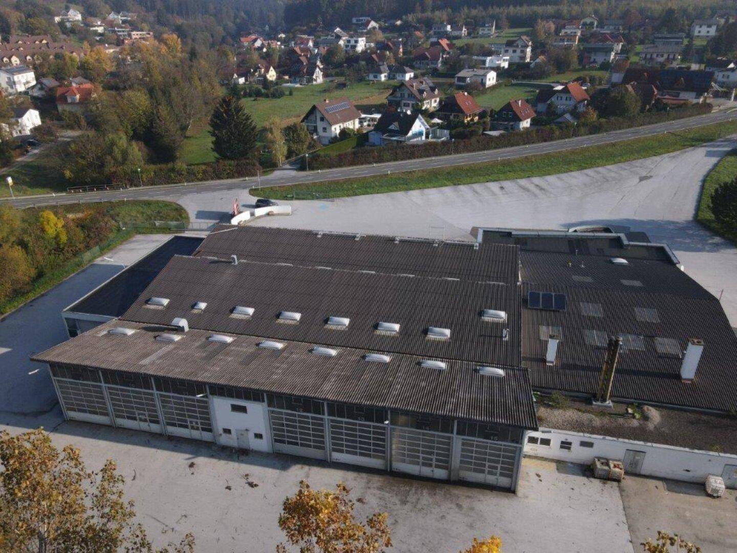 Weitläufige Luftaufnahme des Gewerbekomplexes mit angrenzenden Wohngebieten und viel Grünfläche.