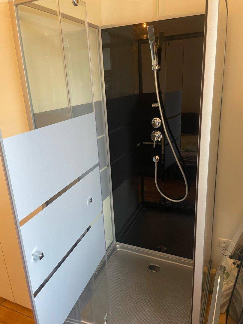Moderne Duschkabine mit Regenduschkopf und Handbrause in minimalistischem Design.