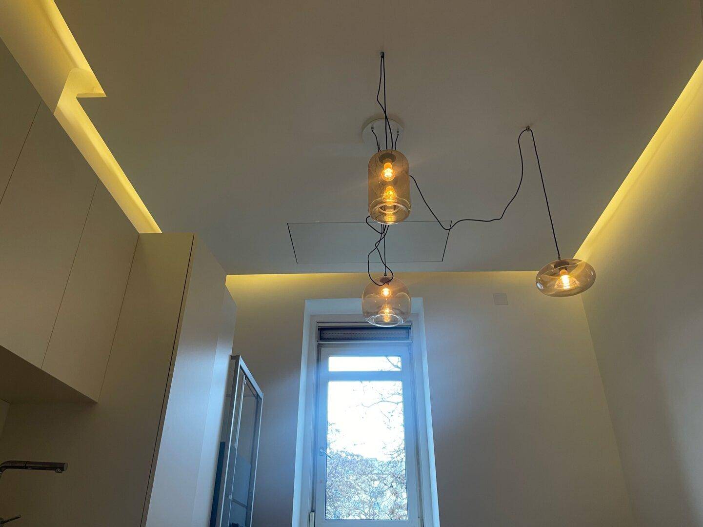 Decke mit moderner Beleuchtung und einem Fenster, das natürliches Licht hereinlässt.