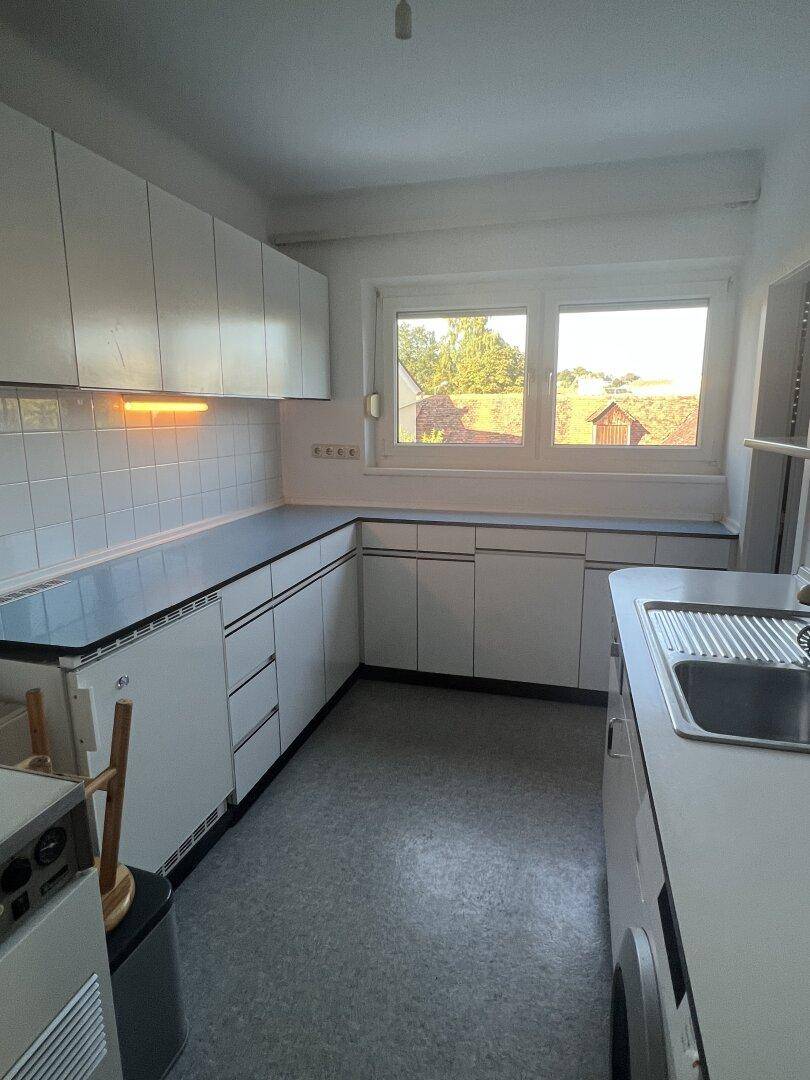 Funktionale Küche mit weißen Schränken, blauen Arbeitsplatten und Fliesenrückwand.