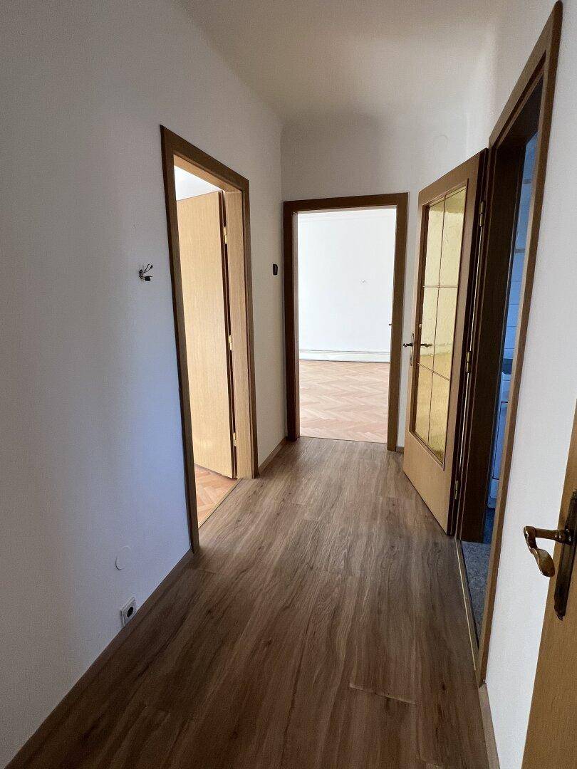 Heller Flur mit Laminatboden und mehreren Türen zu den angrenzenden Zimmern.