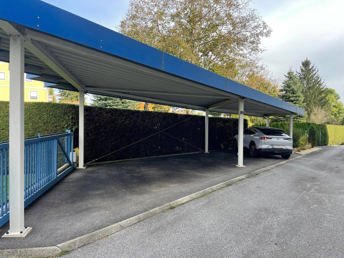 Geräumiger Carport mit blauem Dach, bietet geschützten Parkplatz für Fahrzeuge.