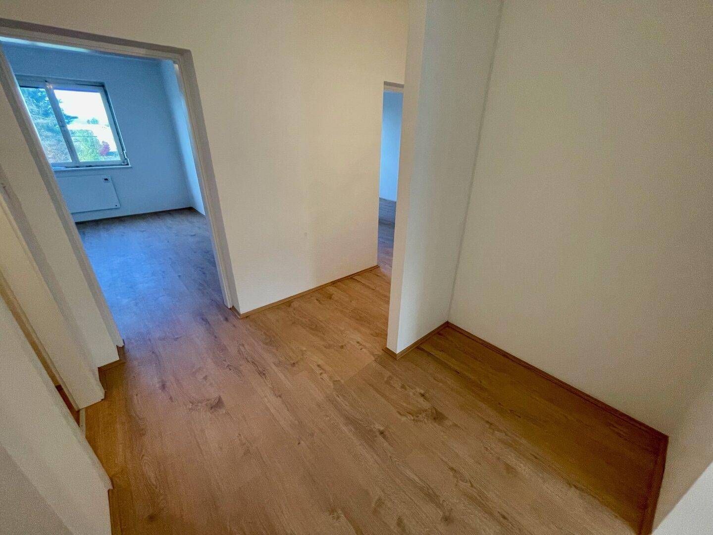 Geräumiger Flur mit Holzfußboden und offenen Durchgängen zu verschiedenen Zimmern.