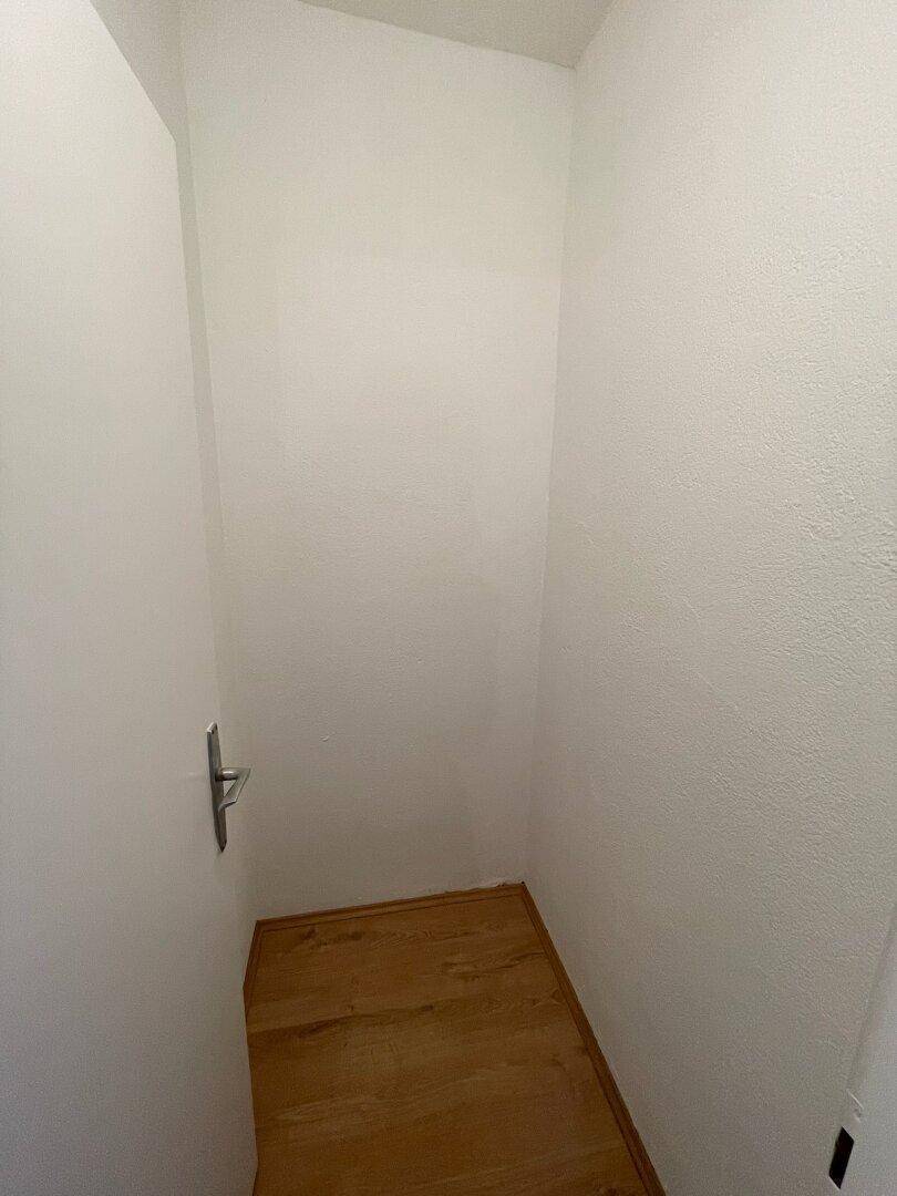Kleiner Abstellraum mit Holzfußboden und weißen Wänden für zusätzlichen Stauraum.