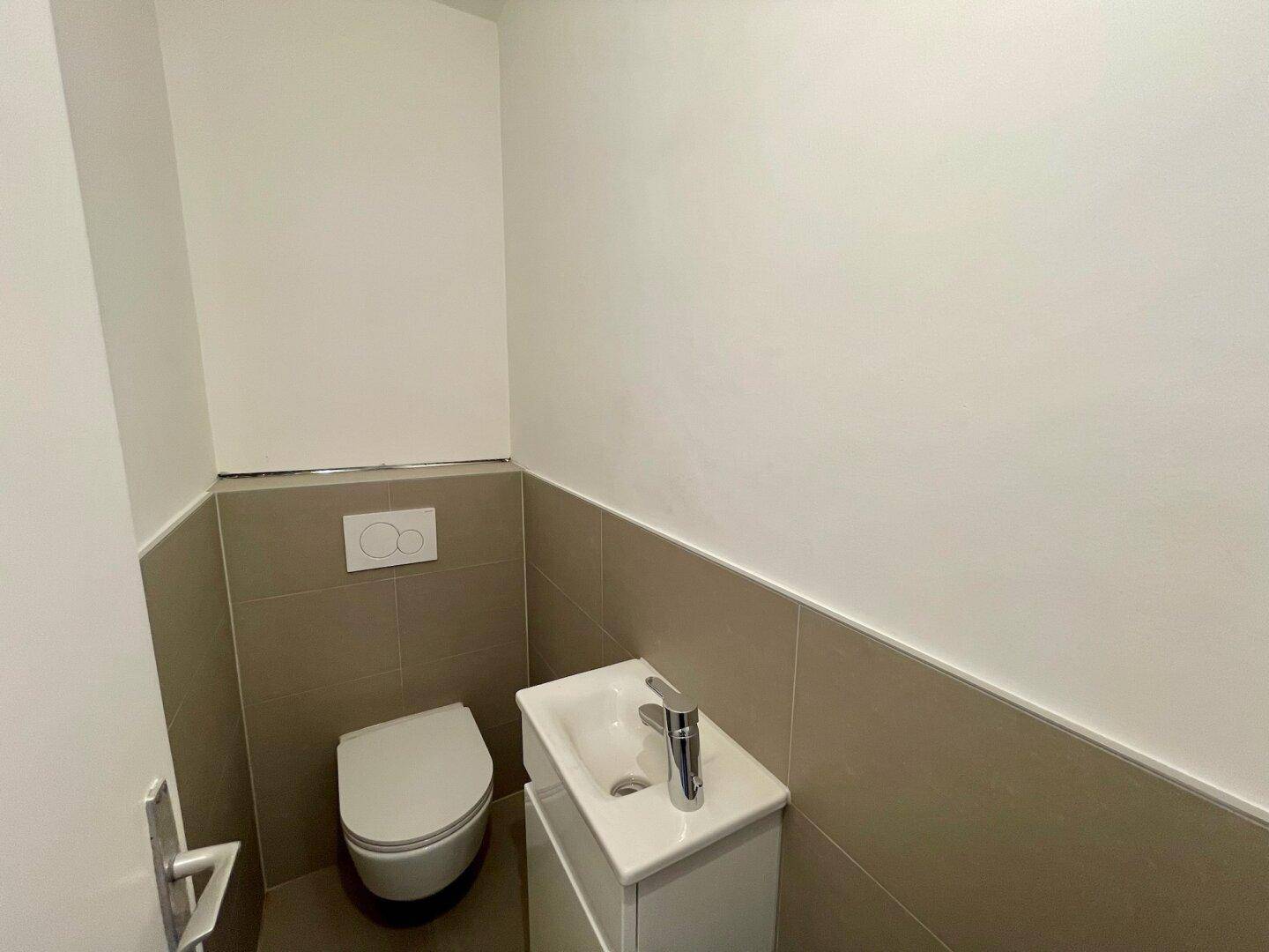 Modernes Gäste-WC mit wandhängender Toilette und kleinem Waschbecken.
