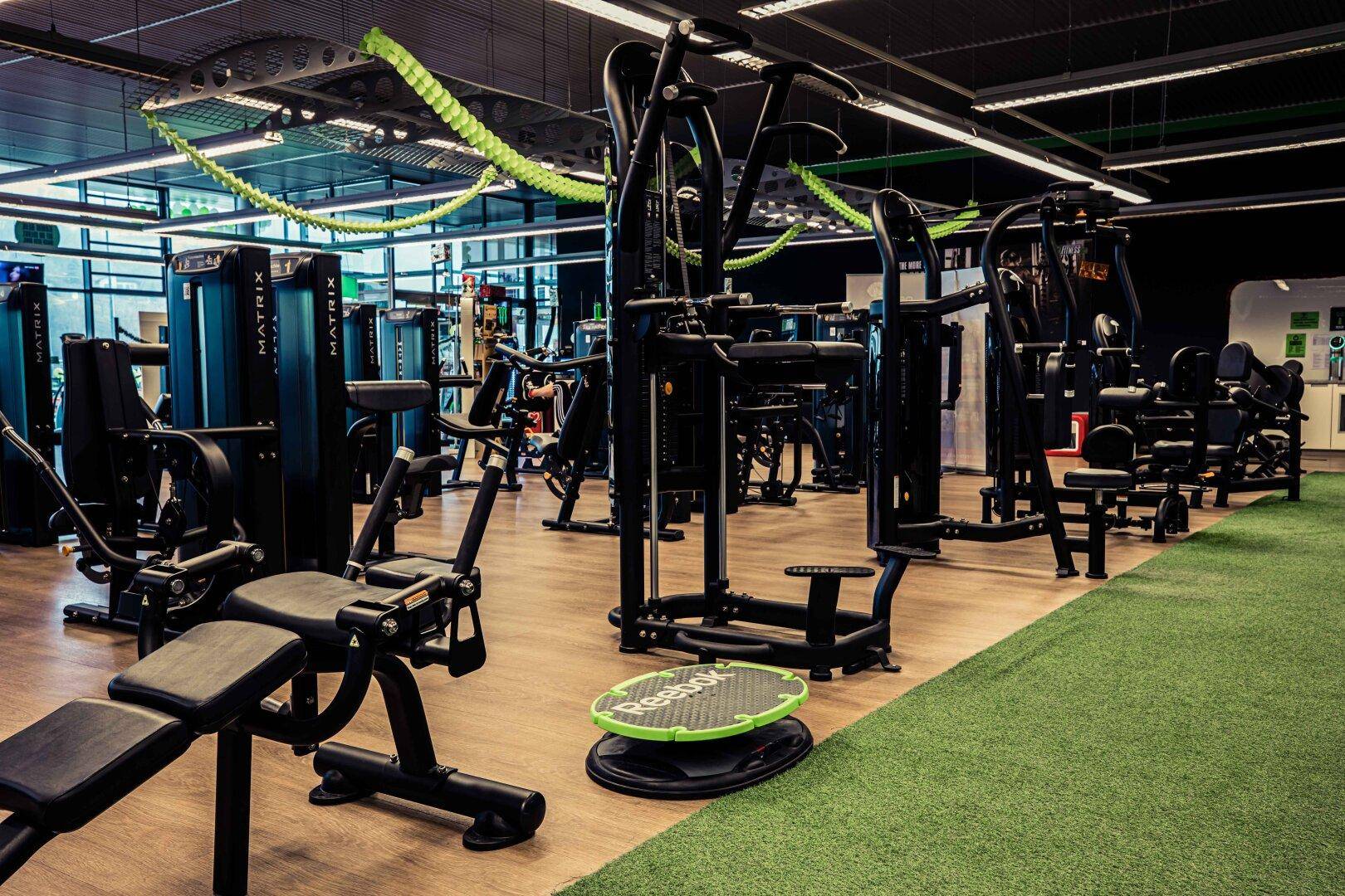 Geräumiger Fitnessbereich mit einer Vielzahl moderner Trainingsgeräte und Holzboden.