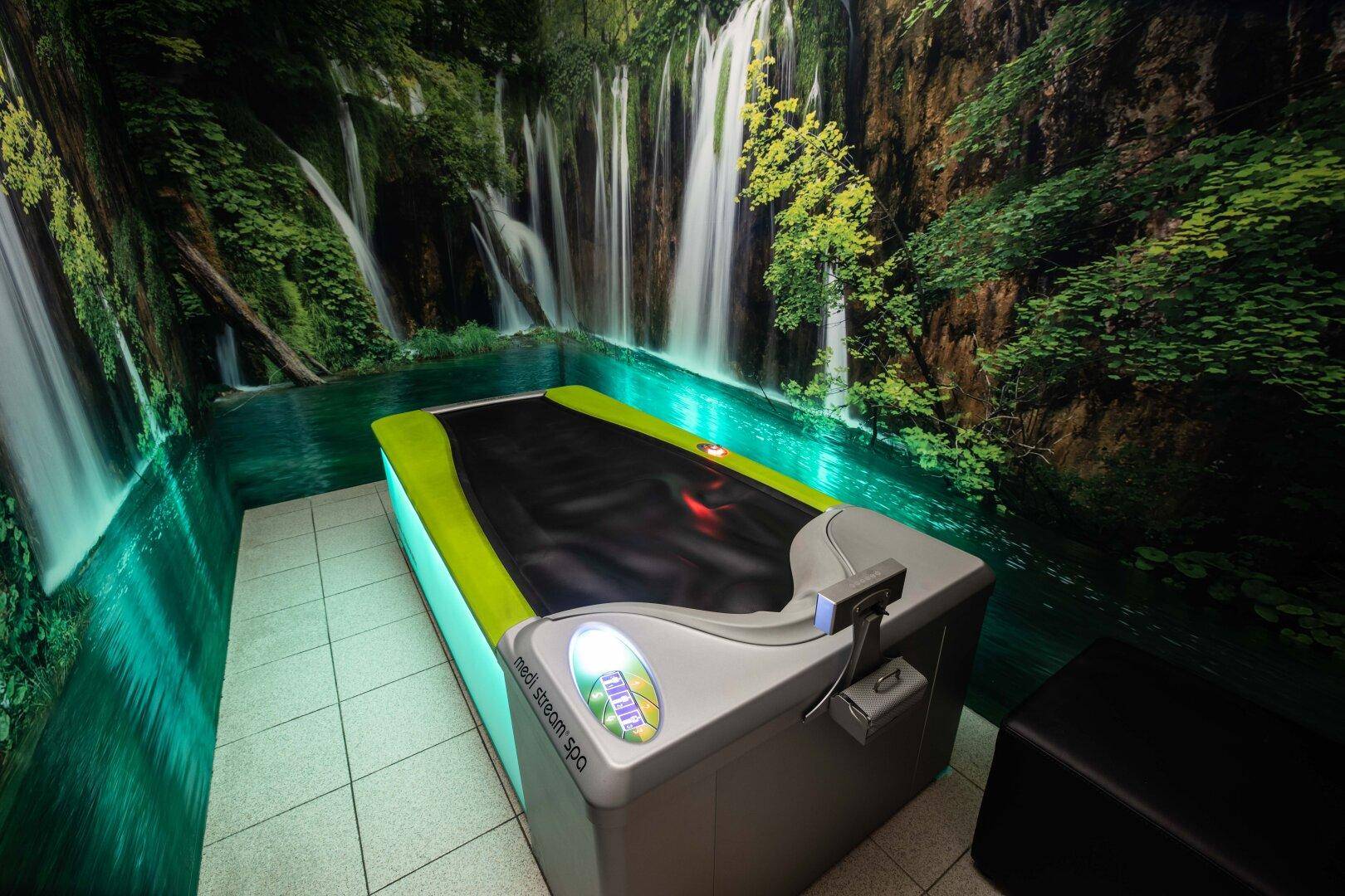 Entspannungsraum mit einem Hydrojet-Massagebett und einer Wandtapete mit Wasserfallmotiv.