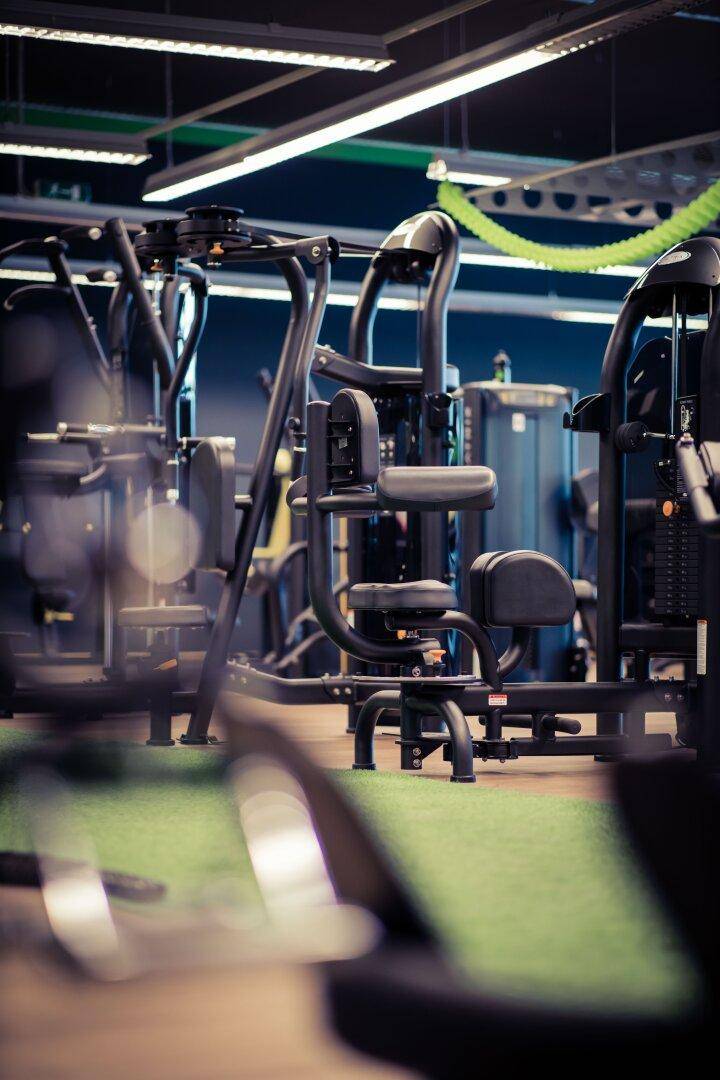 Nahaufnahme von modernen Krafttrainingsgeräten in einem Fitnessstudio mit Kunstrasenboden.