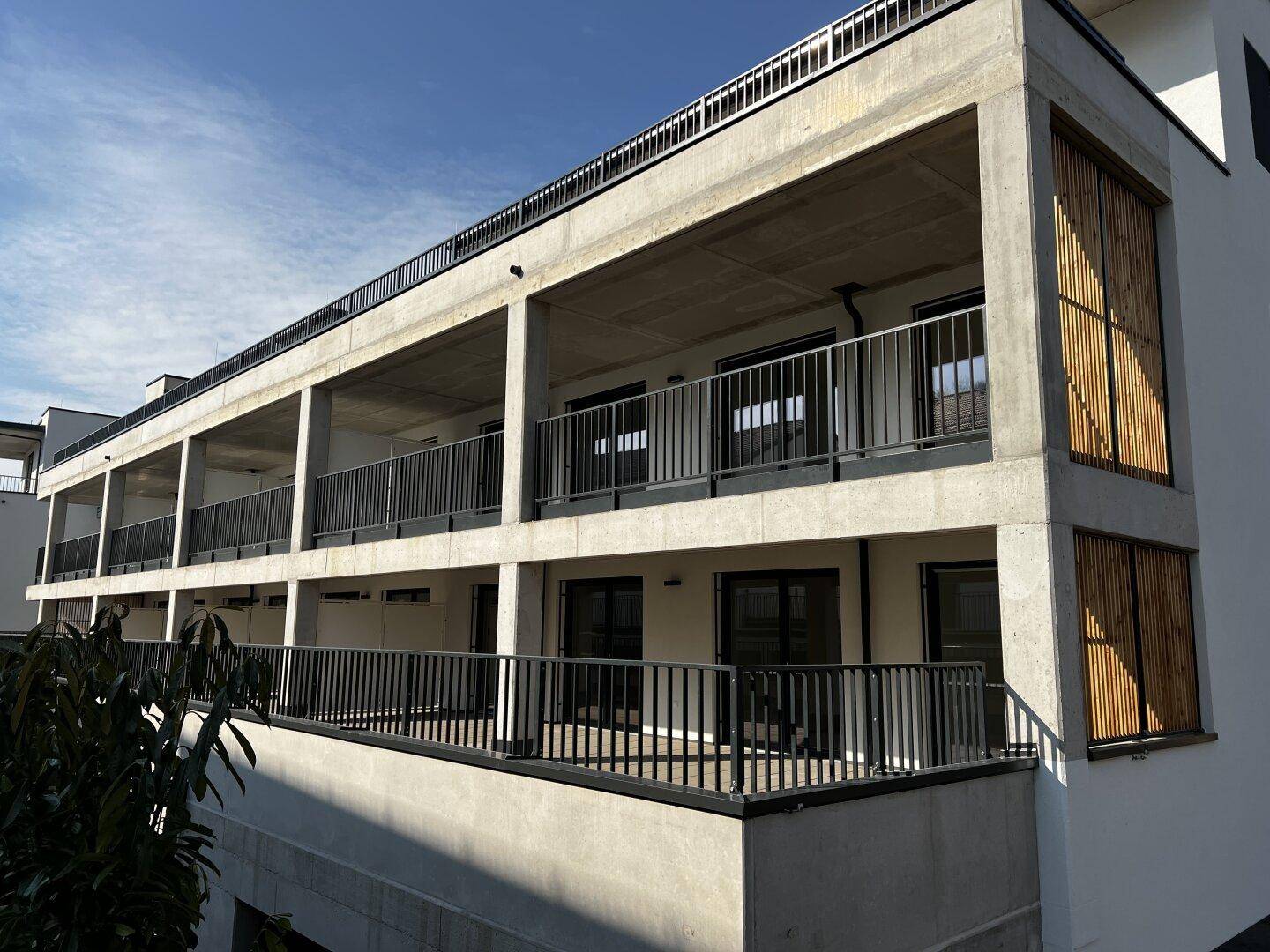 Moderne Wohnanlage mit mehreren Loggien und Balkonen unter blauem Himmel.